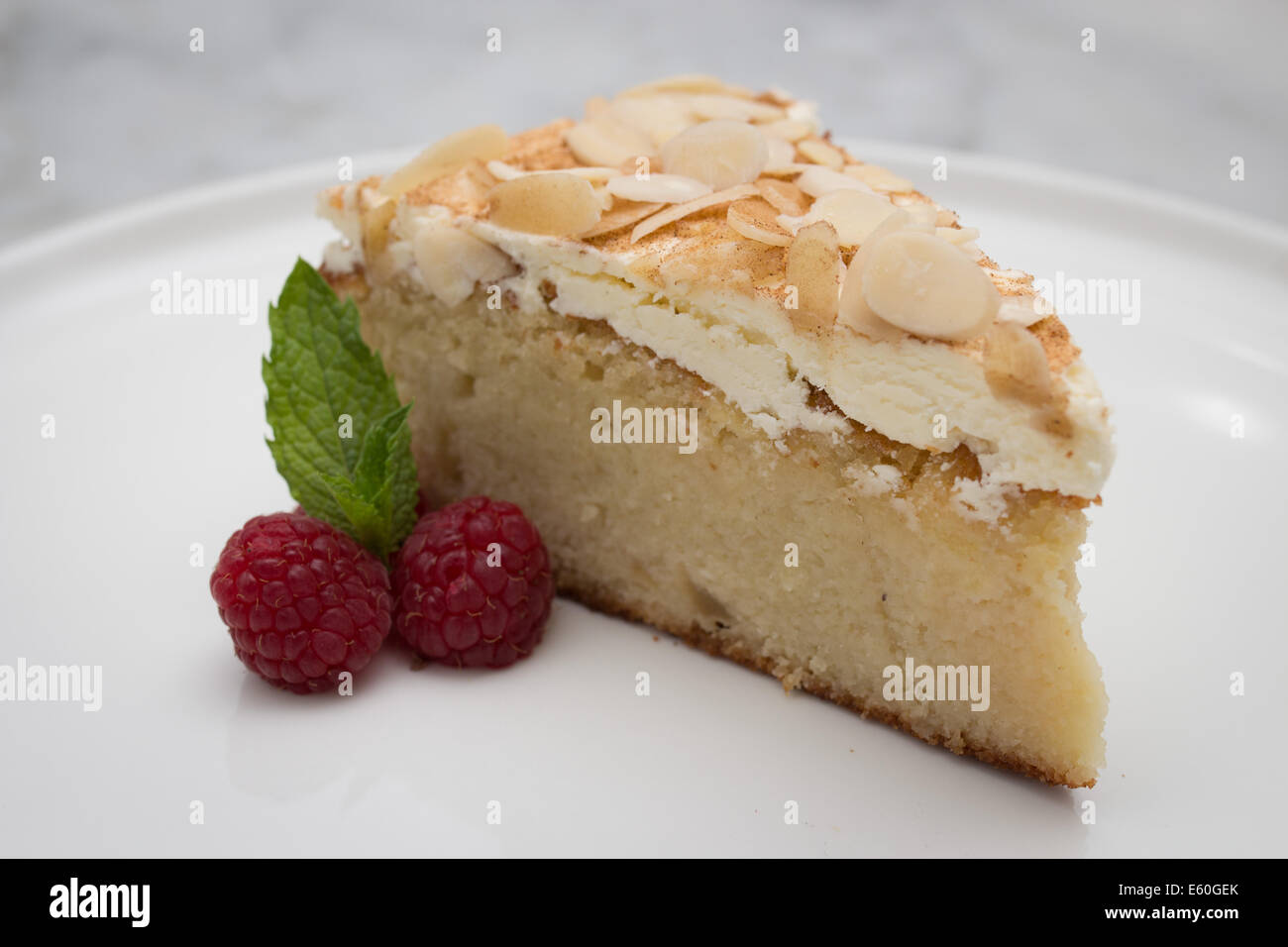 A slice of gluten free almond cake dressed with raspberries and mint Stock Photo