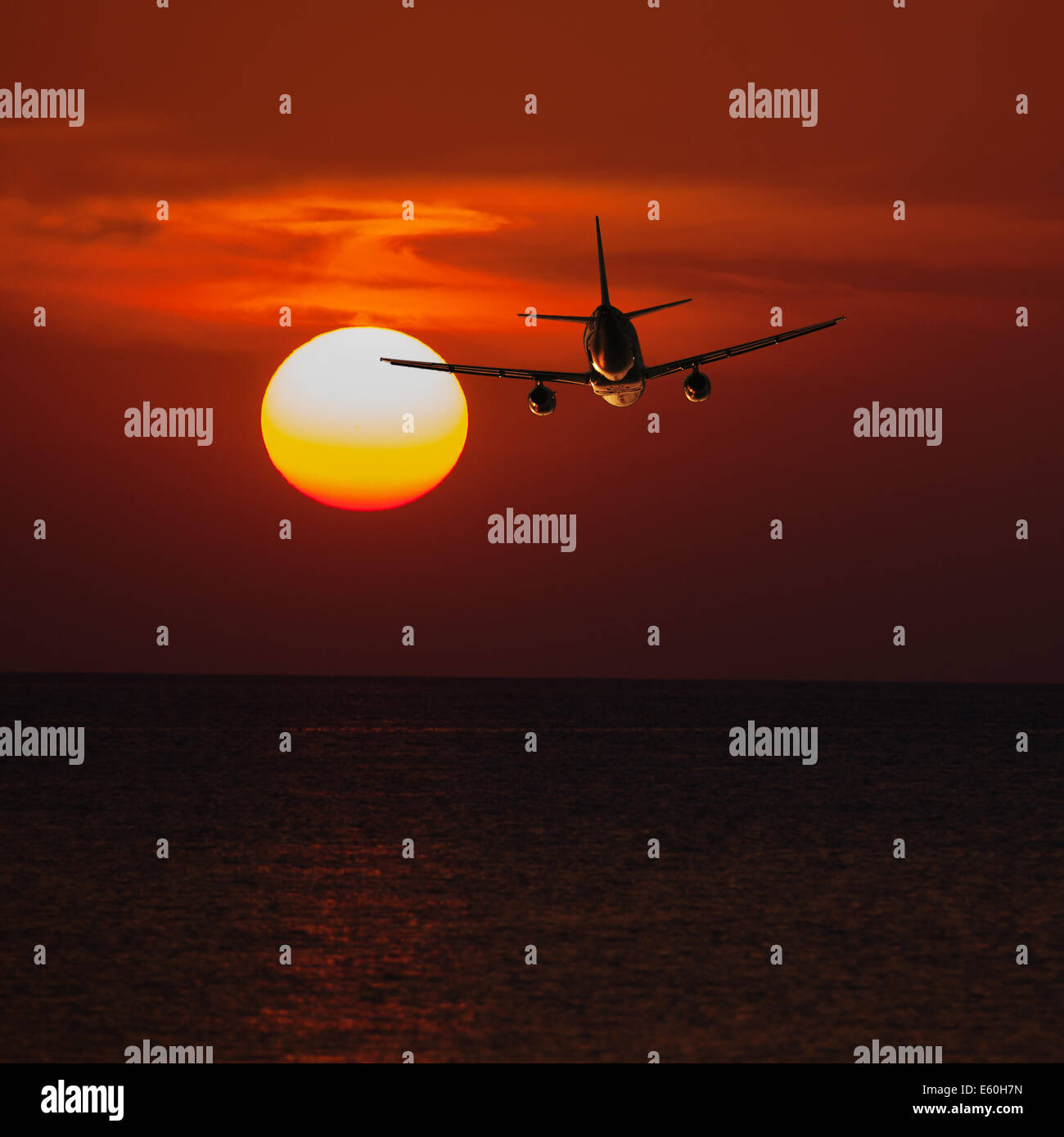 Passenger plane flying at a low altitude at sunset and the sun background Stock Photo