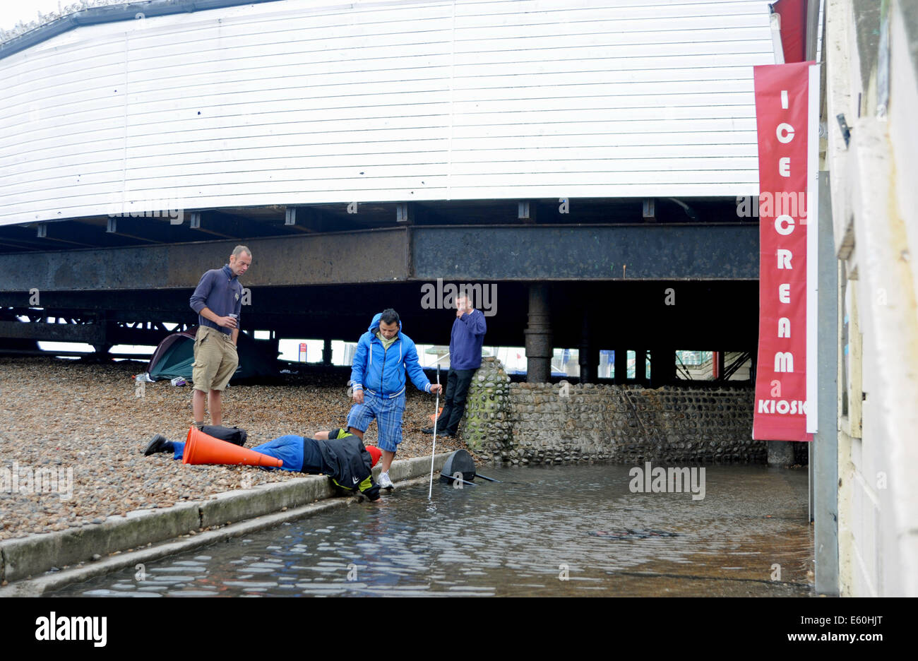 Traders try to clear away floodwater from Brighton seafront during storms following Hurricane Bertha UK Stock Photo