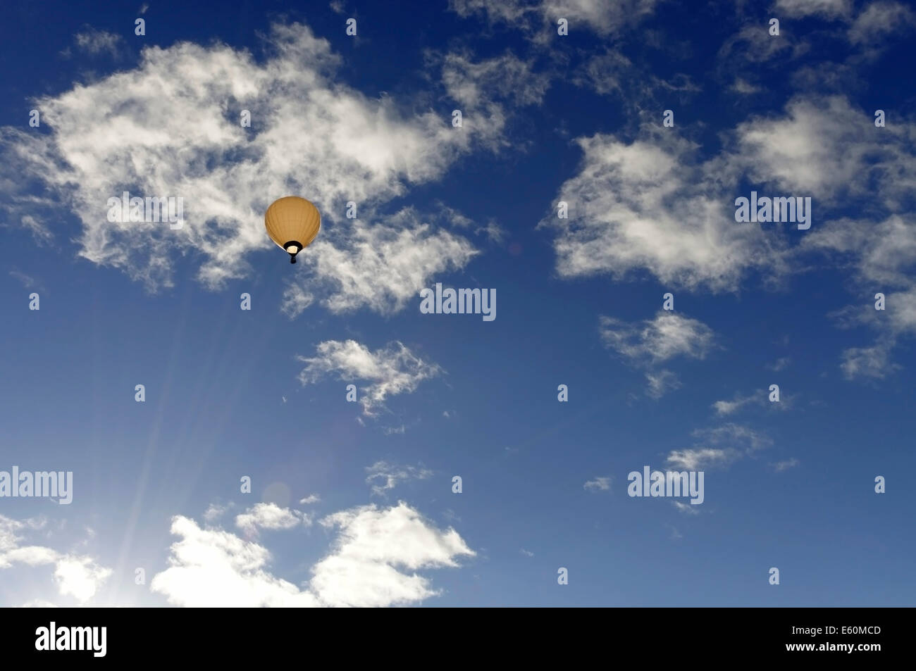 bright hot air balloon high in the sky with a blue sky and clouds Stock Photo