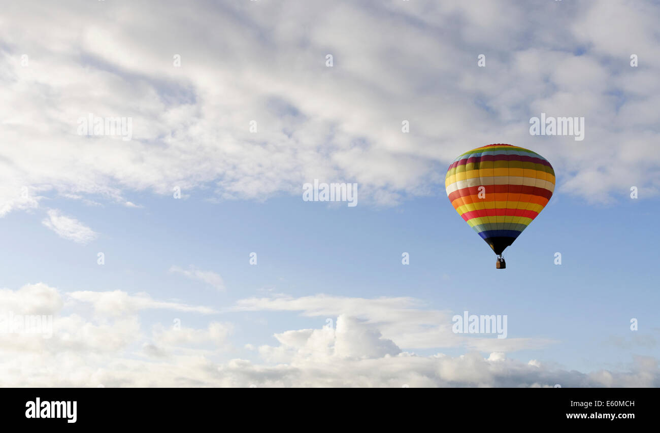 rainbow coloured hot air balloon in sky of light clouds Stock Photo - Alamy