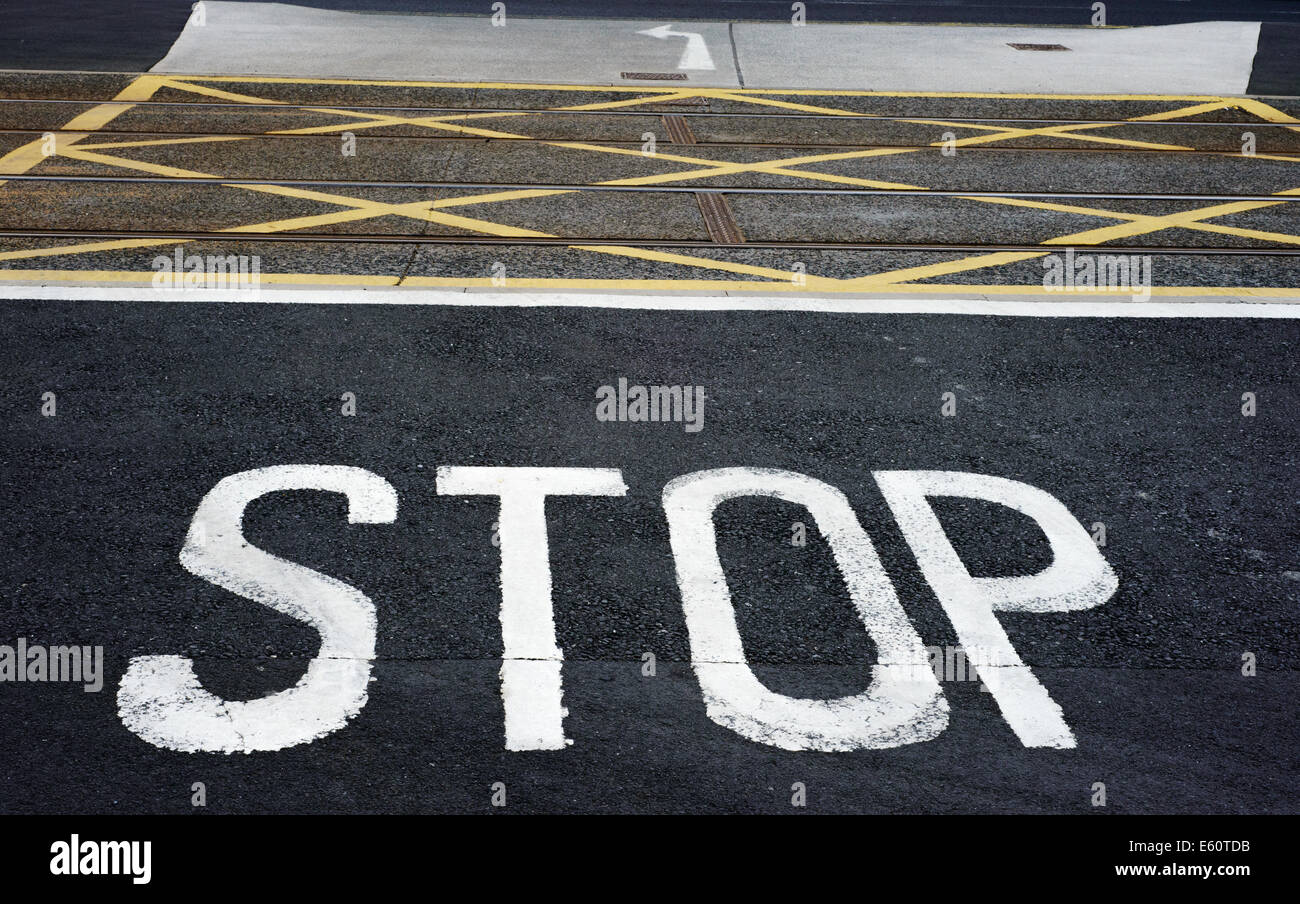 STOP sign painted on road next to tram tracks Stock Photo