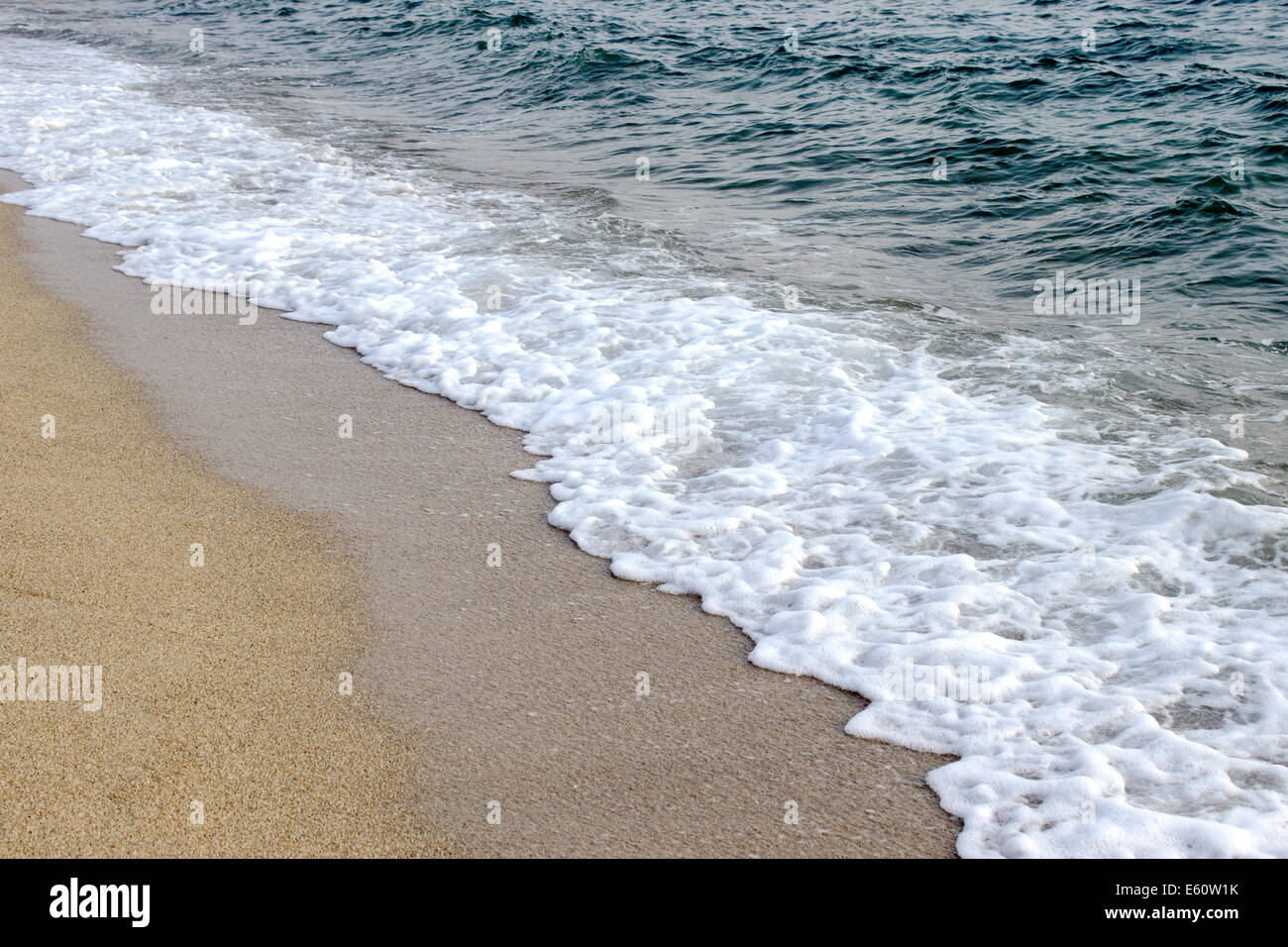 Wave of sea water on a clear gravel beach in summer day Stock Photo