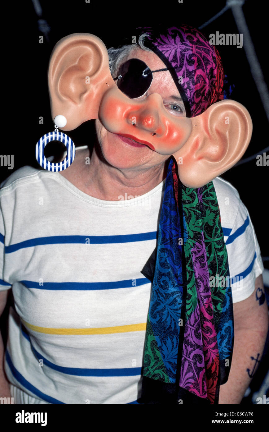 A woman dresses up with a big-eared mask to portray a humorous pirate at a passenger costume party on board a sailing ship in the Caribbean Sea. Stock Photo