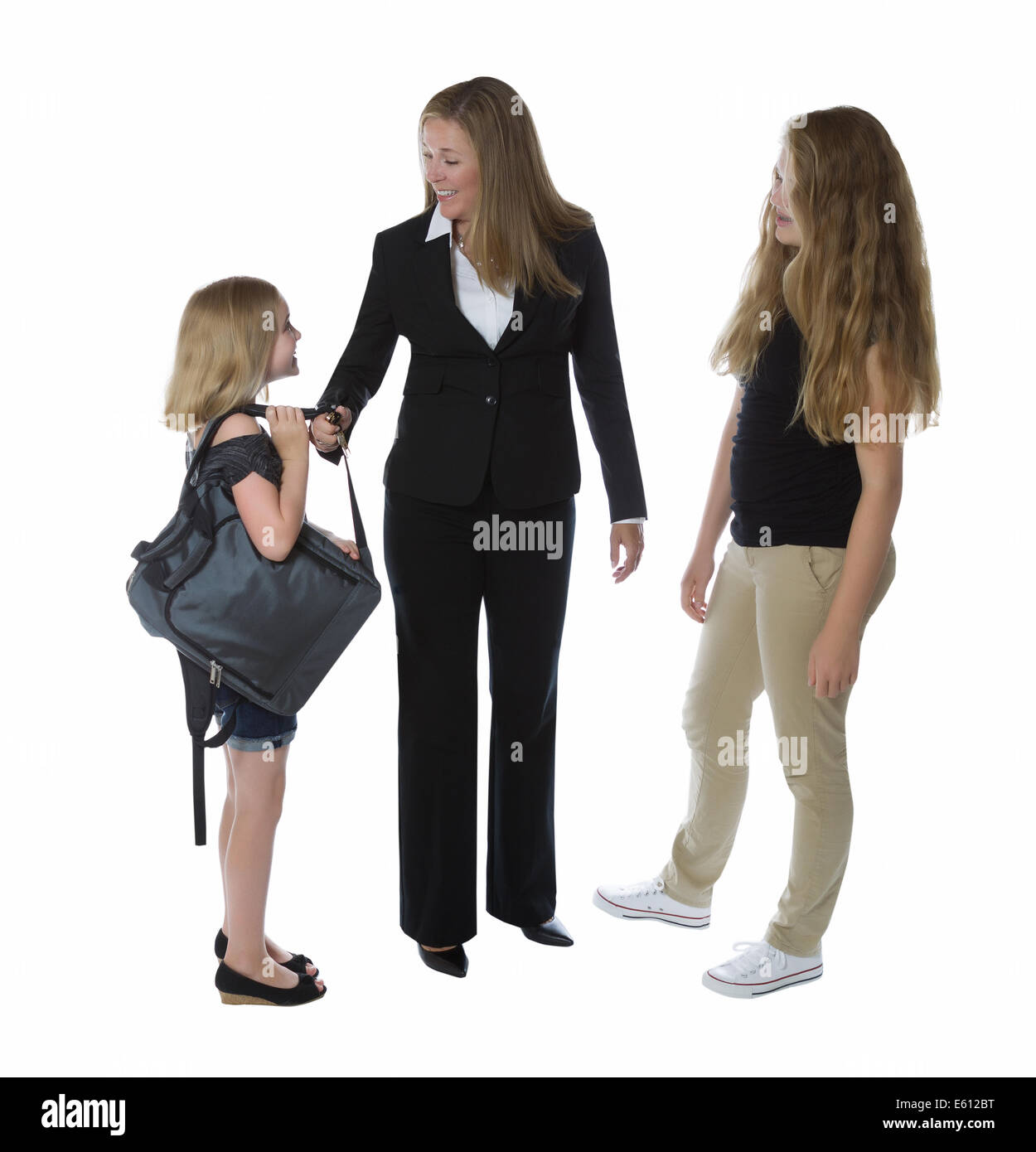 Side view of businesswoman and her young daughters greeting her as she comes home from work isolated on a white background Stock Photo