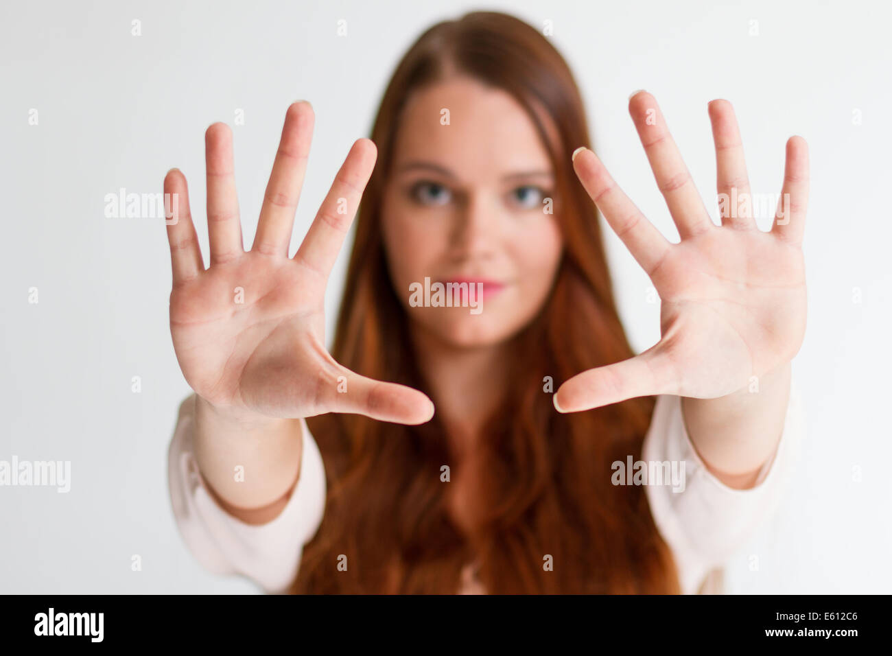 Serious girl asking to stop with hands on a white background Stock Photo