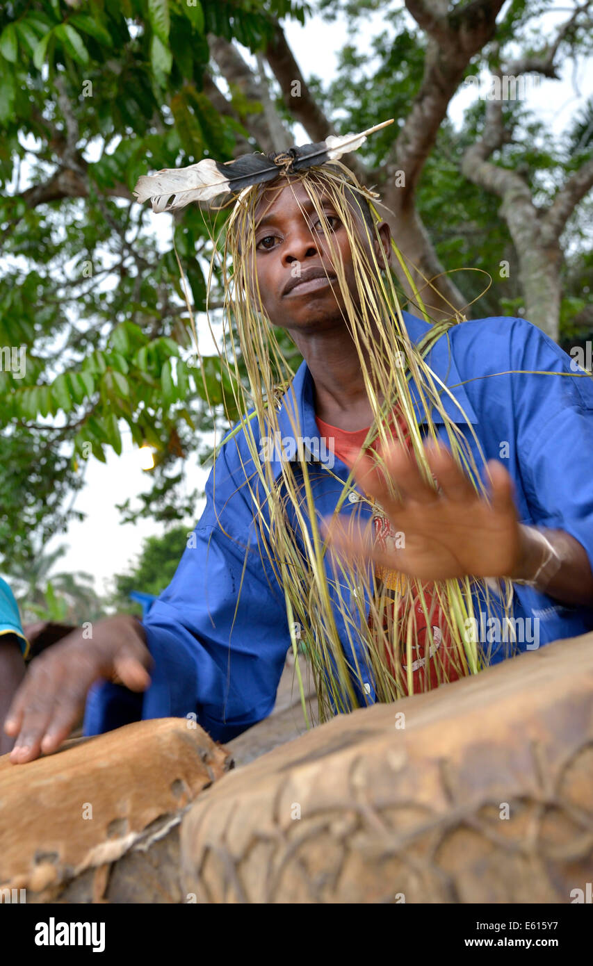 Musician with a headdress made of bast and a feather, playing drums, Nkala, Bandundu Province, Democratic Republic of the Congo Stock Photo