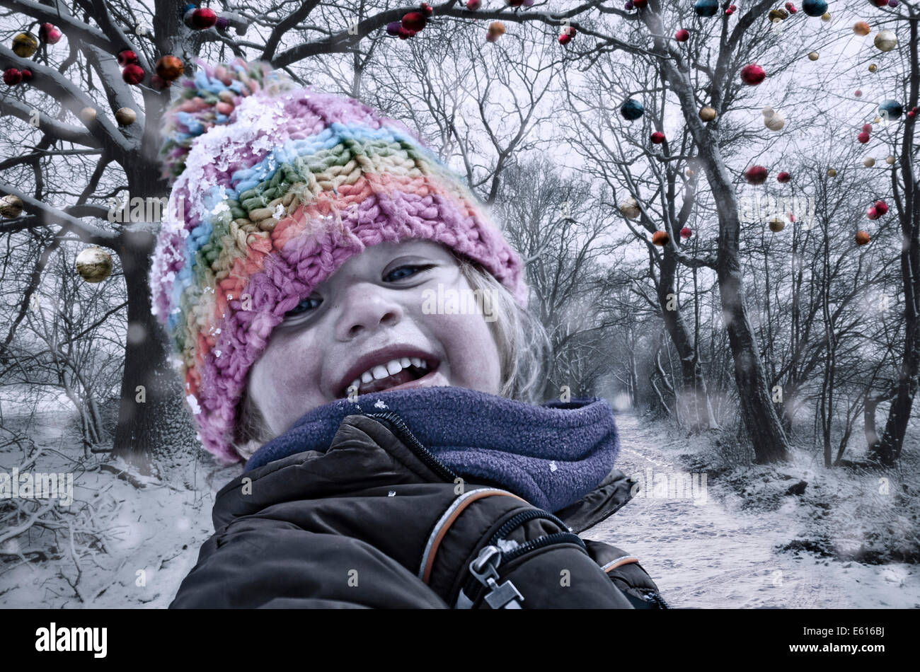 Girl in winter clothing, in front of trees with Christmas baubles Stock Photo
