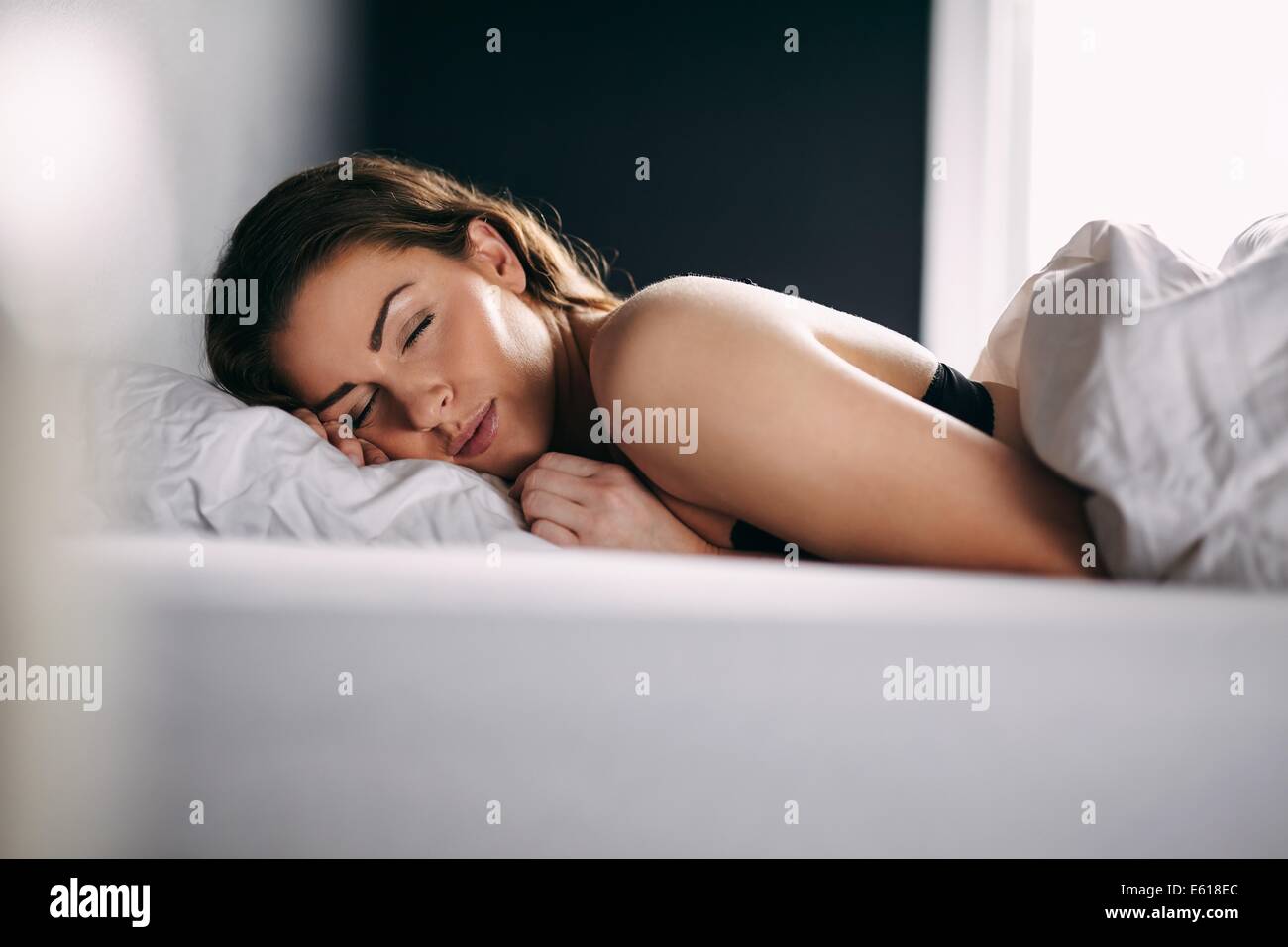 Portrait of relaxed young lady sleeping in her bed. Female model sleeping peacefully in her bed. Stock Photo
