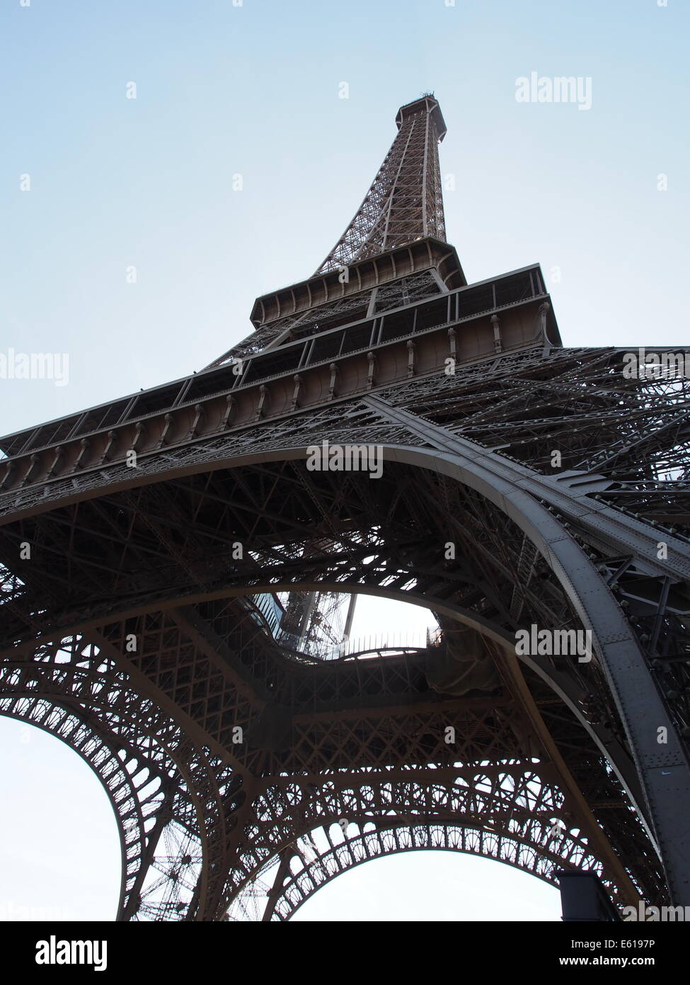 looking up to the top of the Eiffel Tower with blue sky in background Stock Photo