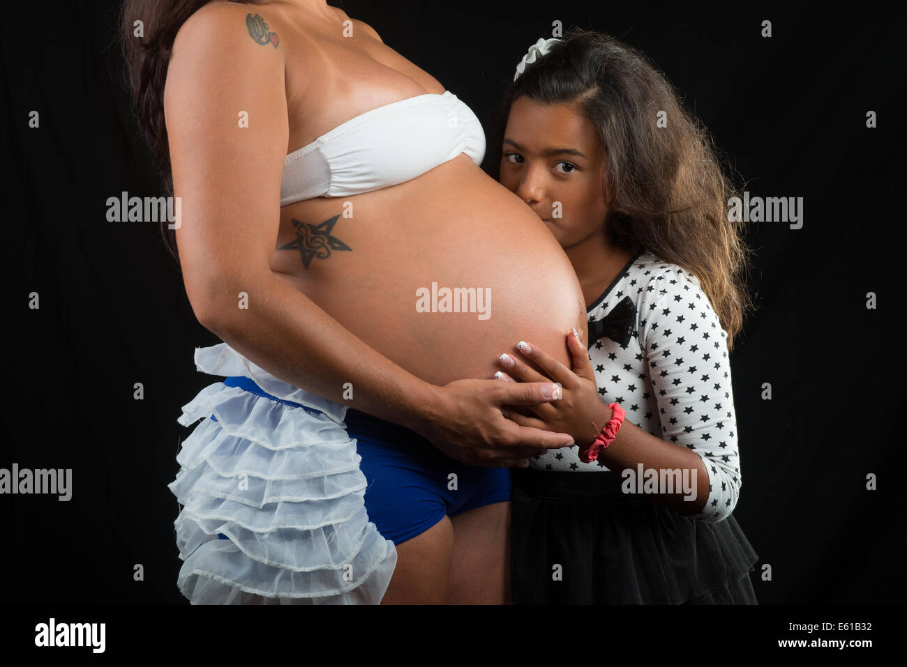 girl kissing her pregnant mother belly Stock Photo