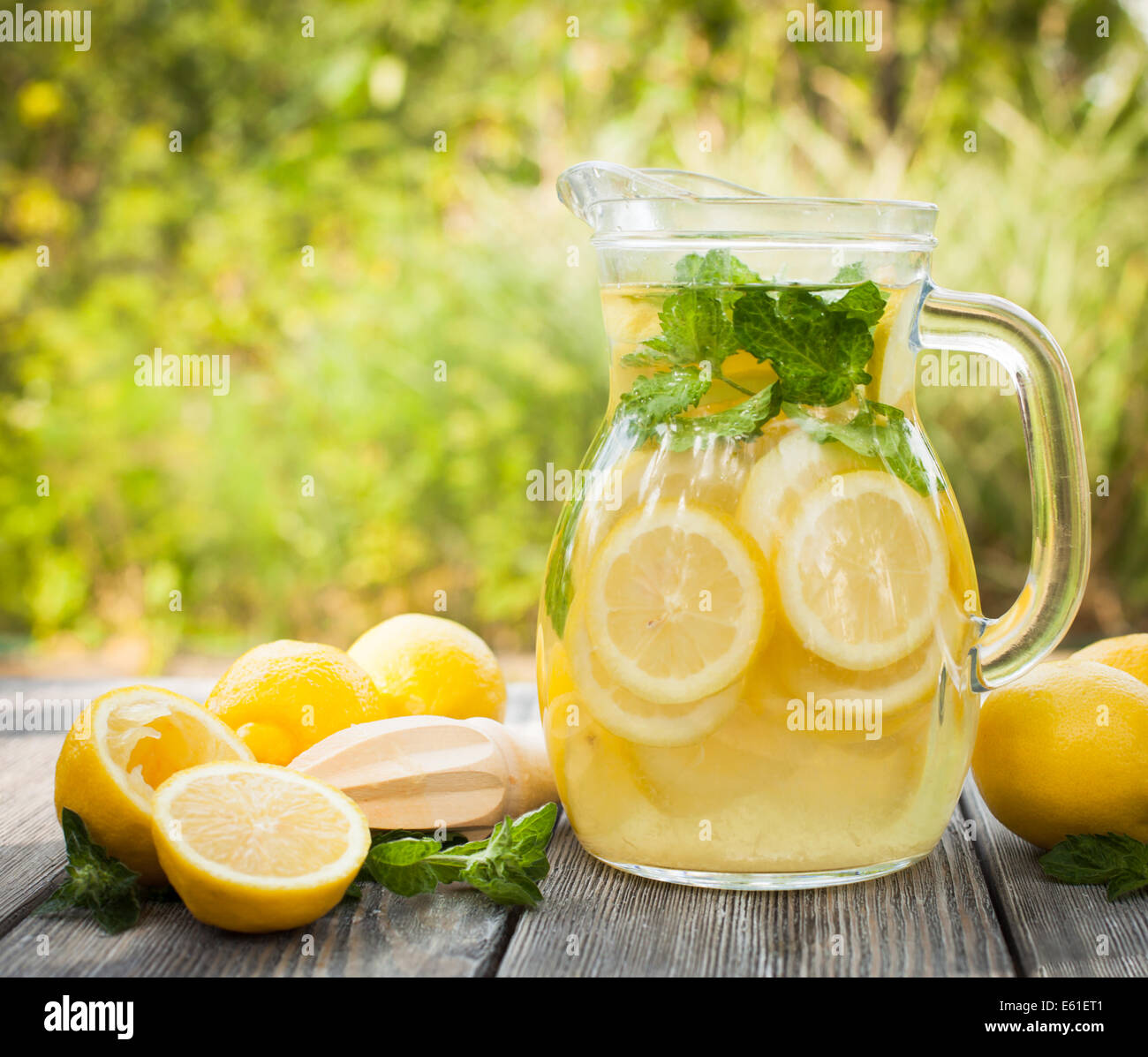 Preparation of the lemonade drink. Lemonade in the jug and lemons with mint on the table outdoor