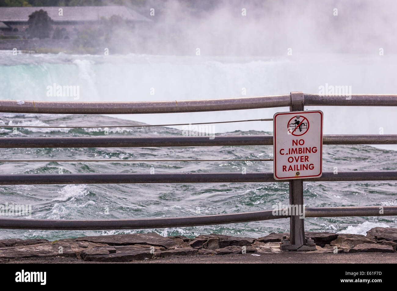 A 'no climbing over railing' sign at the edge of the Niagara Falls. Stock Photo