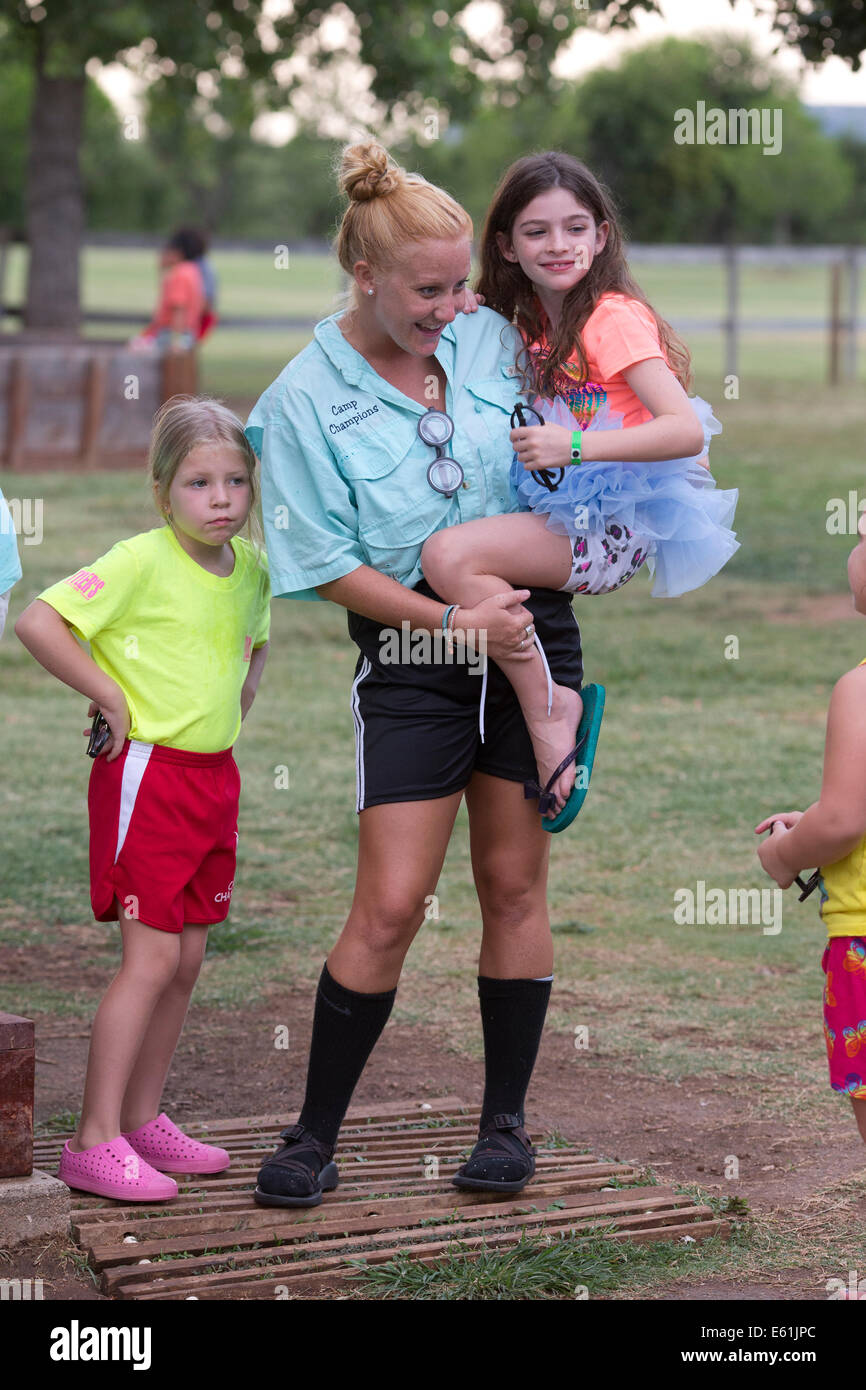 Female counselor holds girl camper in costume at Camp Champions, a sleep-over summer camp on Lake LBJ in Central TX Stock Photo