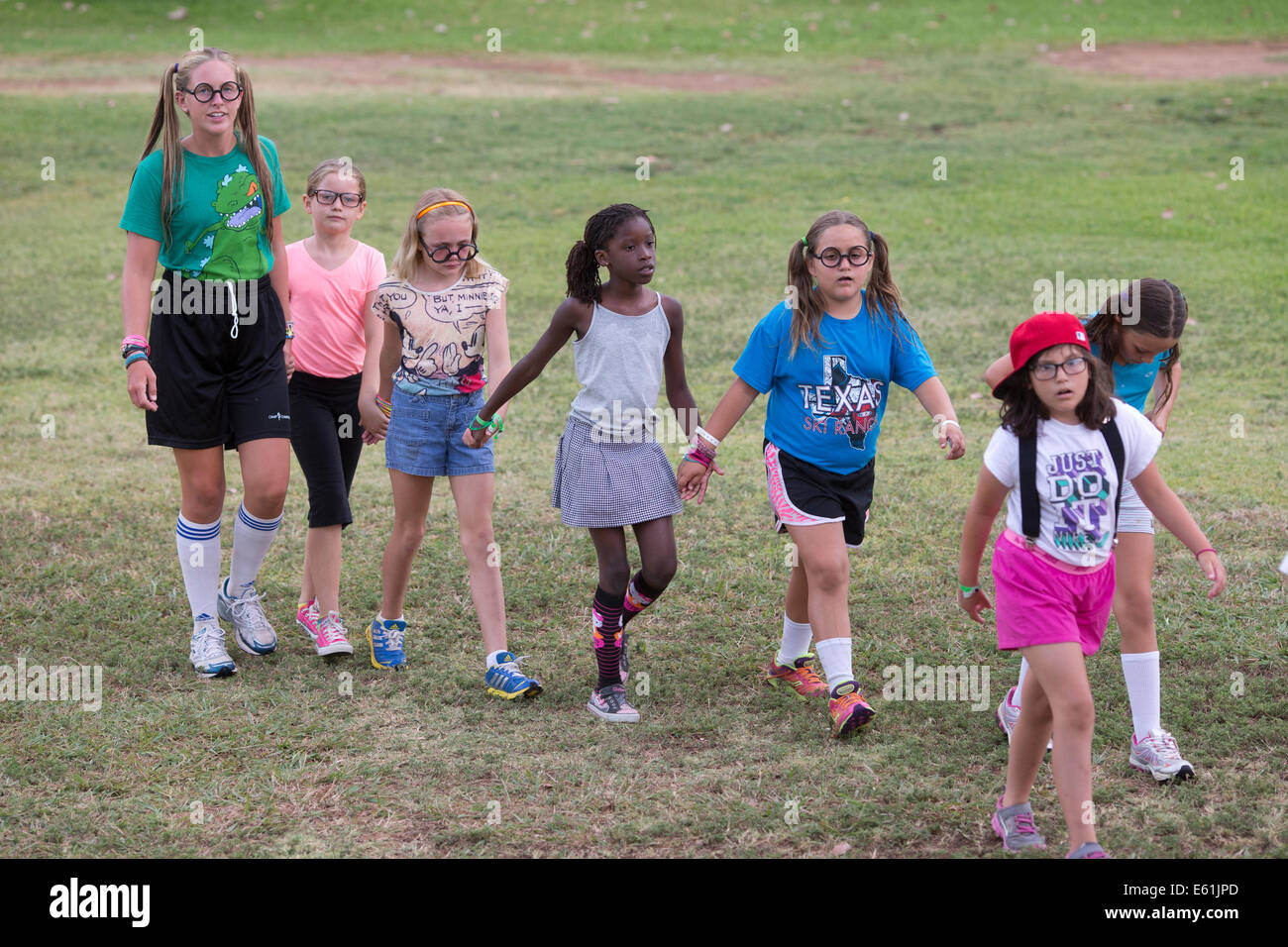 Young girls and counselor walk across field at Camp Champions, a sleep-over summer camp on Lake LBJ in Central TX Stock Photo