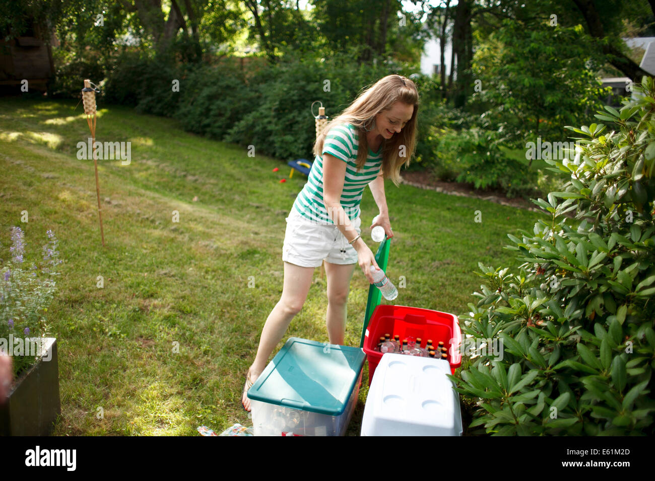 Woman Taking Bottle of Water from Ice Chest at Backyard Barbeque Stock Photo
