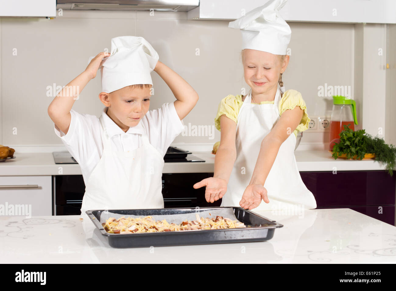 Two Little Chefs Bake Food for Lunch at the Kitchen Stock Photo