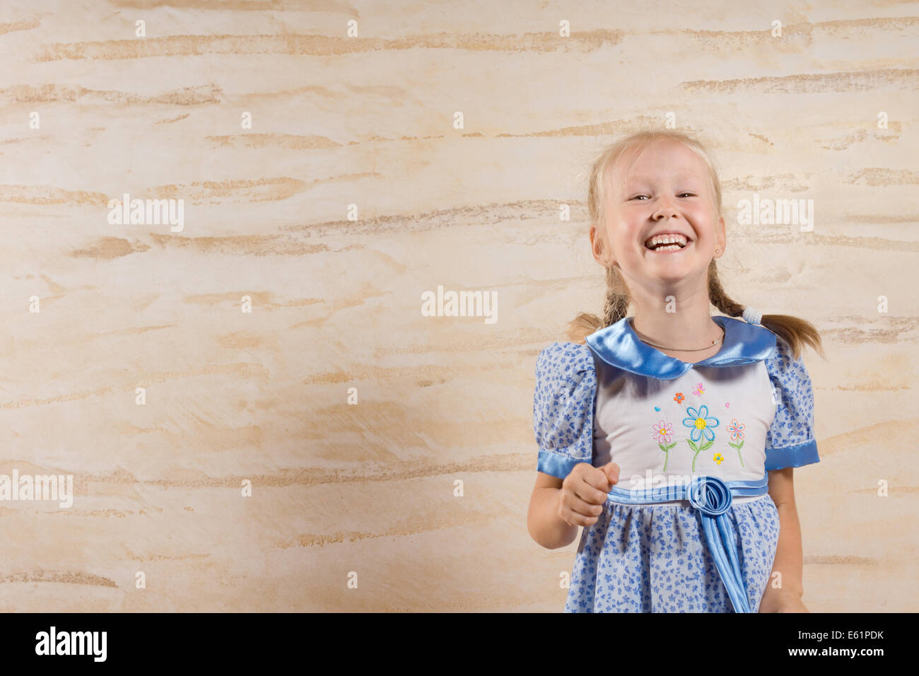 Beautiful merry little girl in a blue summer dress with her blond hair ...