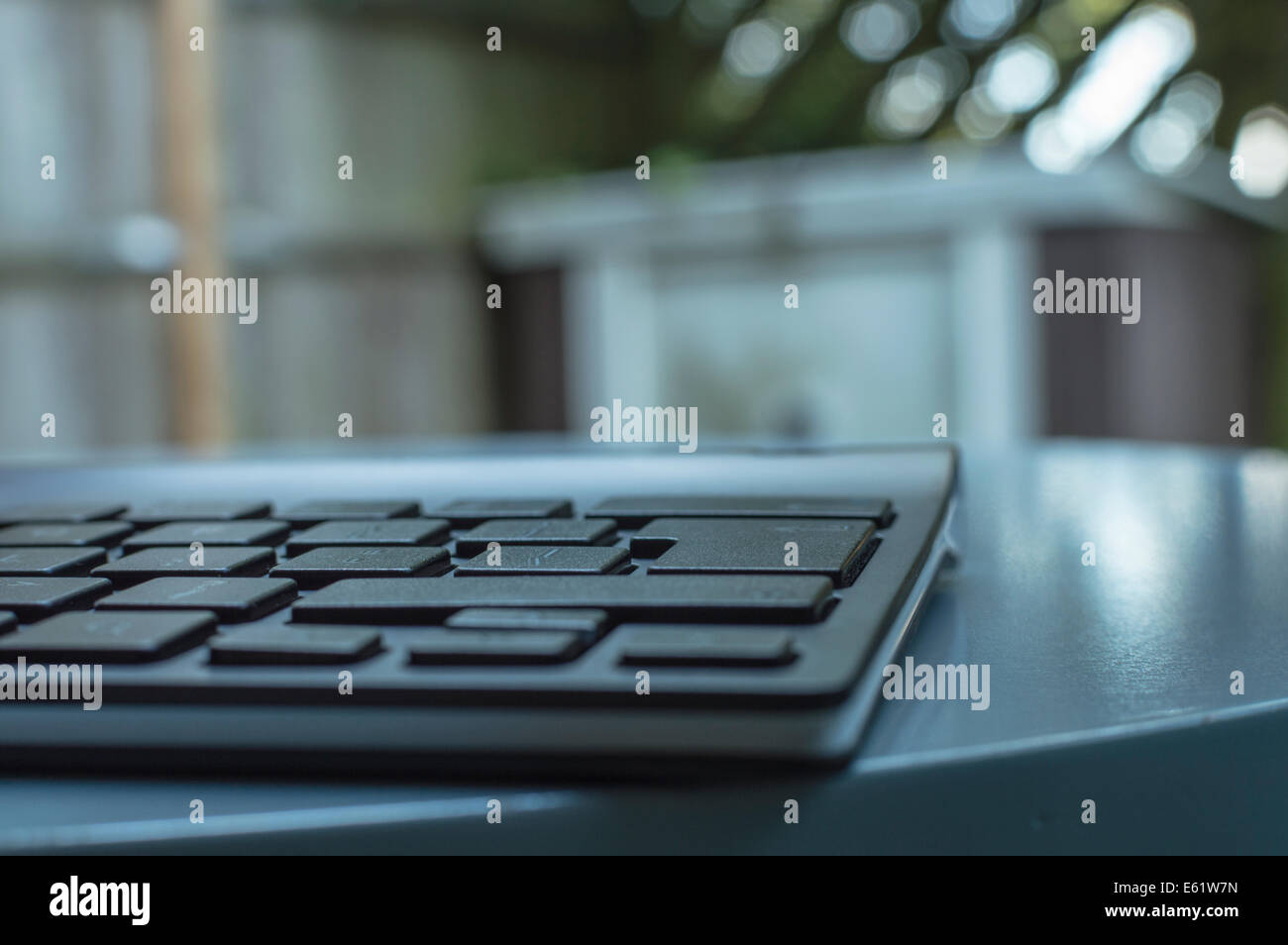 close up of the keys of a thin Bluetooth computer keyboard resting on a table surface. Stock Photo