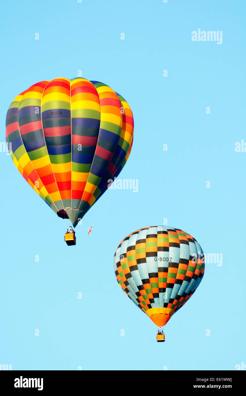 A pair of colourful hot air balloon in flight with blue sky behind during the Bristol Balloon fiesta held annually Stock Photo