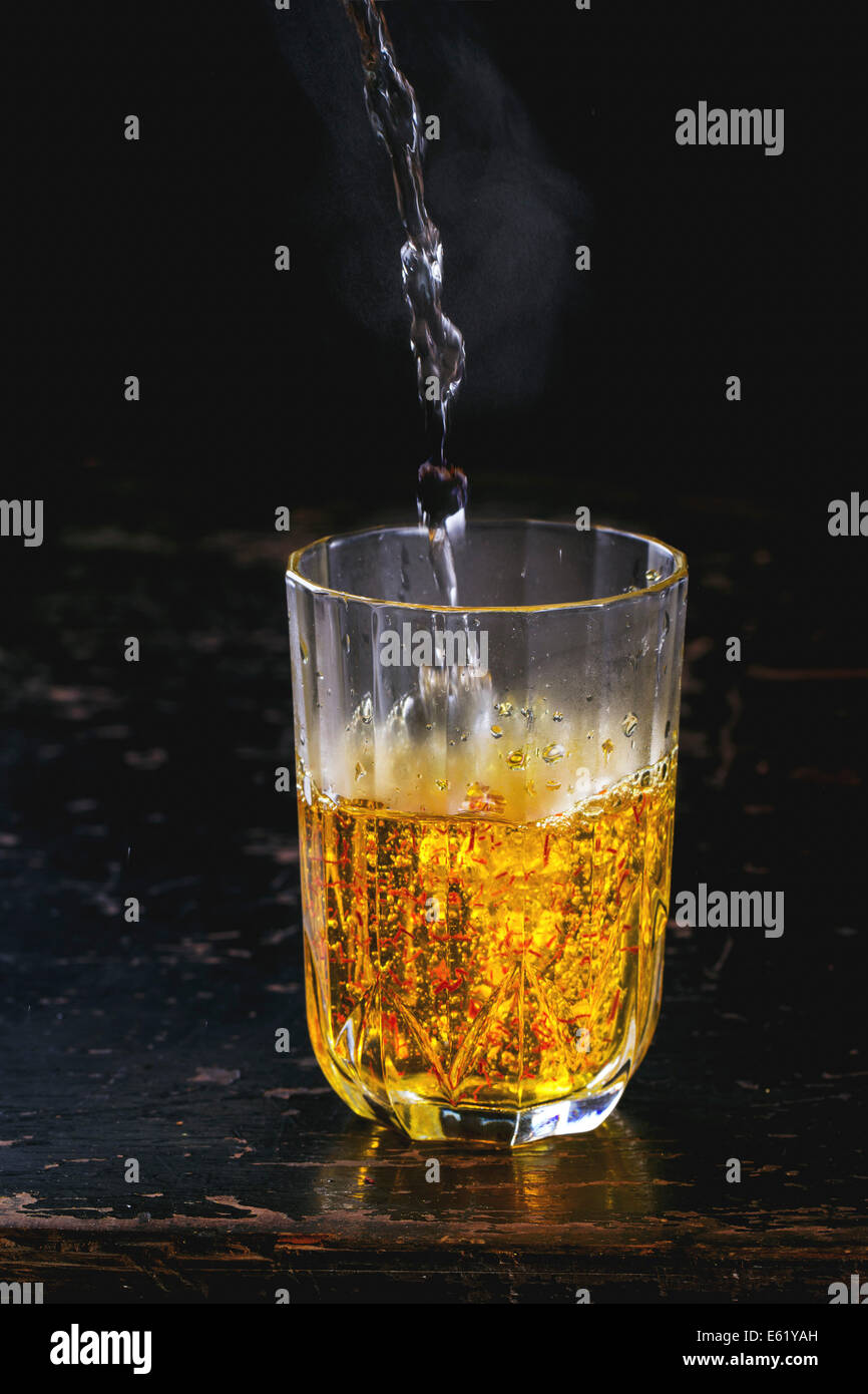 Vintage glass with saffron flowers and pouring hot water Stock Photo