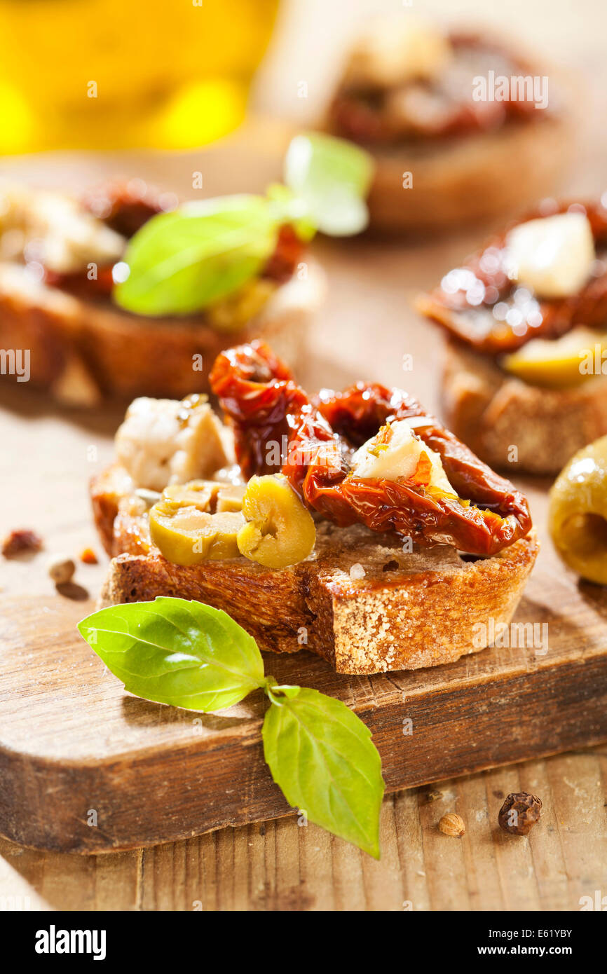 Italian appetizer bruschetta with olive oil, olives, sun-dried tomatoes and cheese. Stock Photo