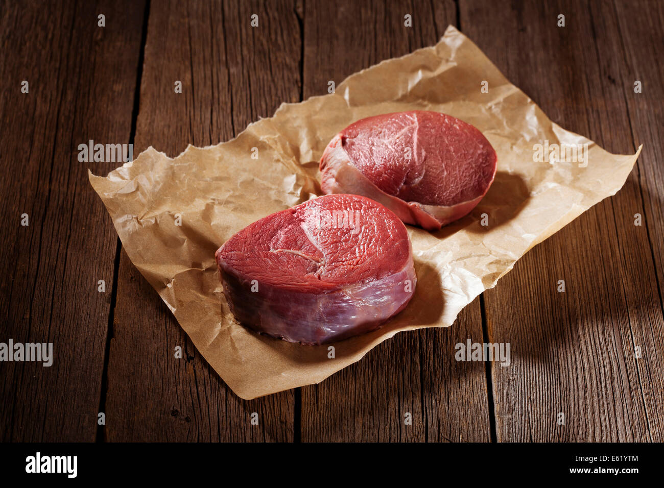 Raw beef steak on wooden table. Stock Photo