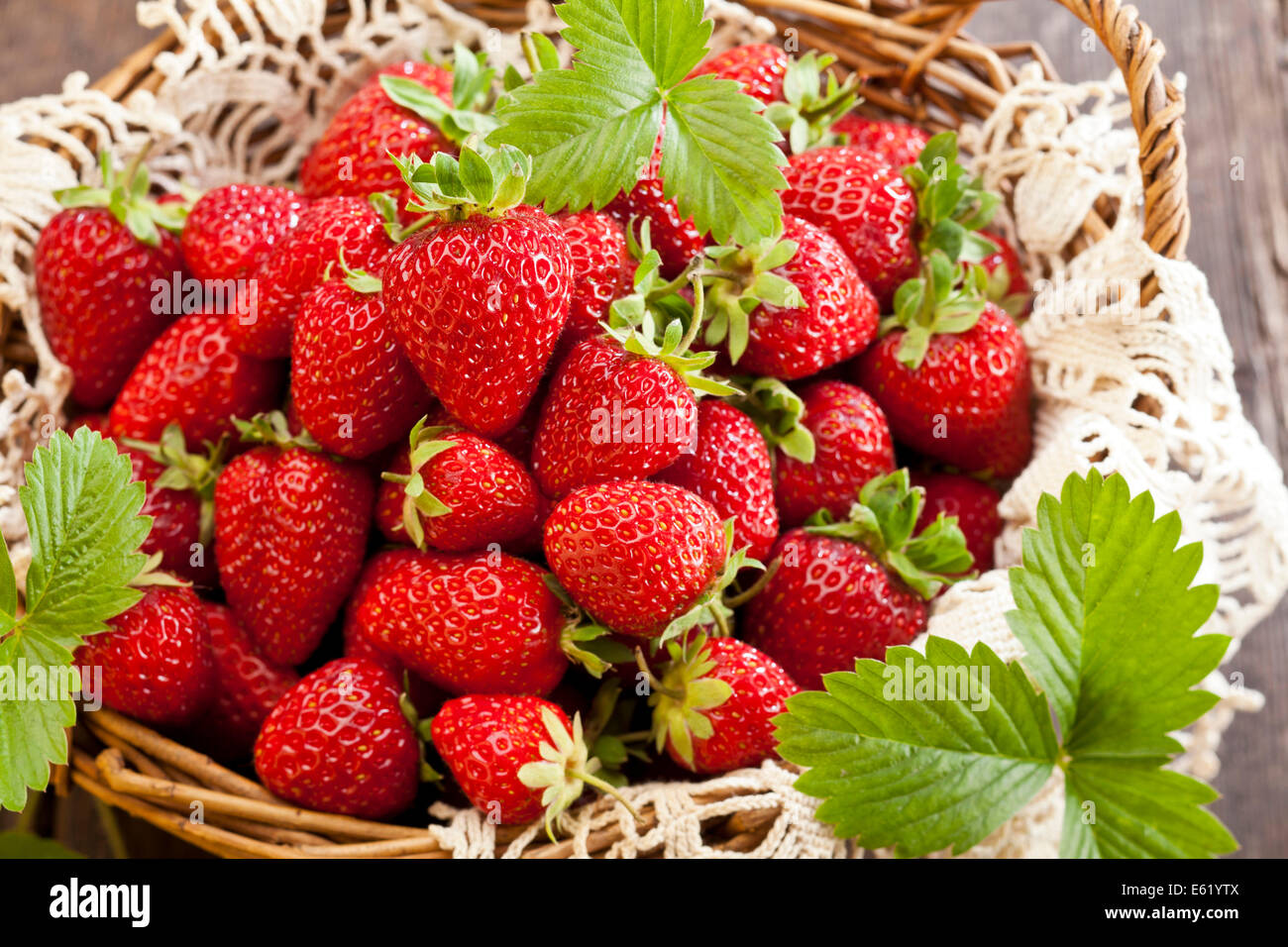 Strawberries in basket on rustic wooden background Stock Photo