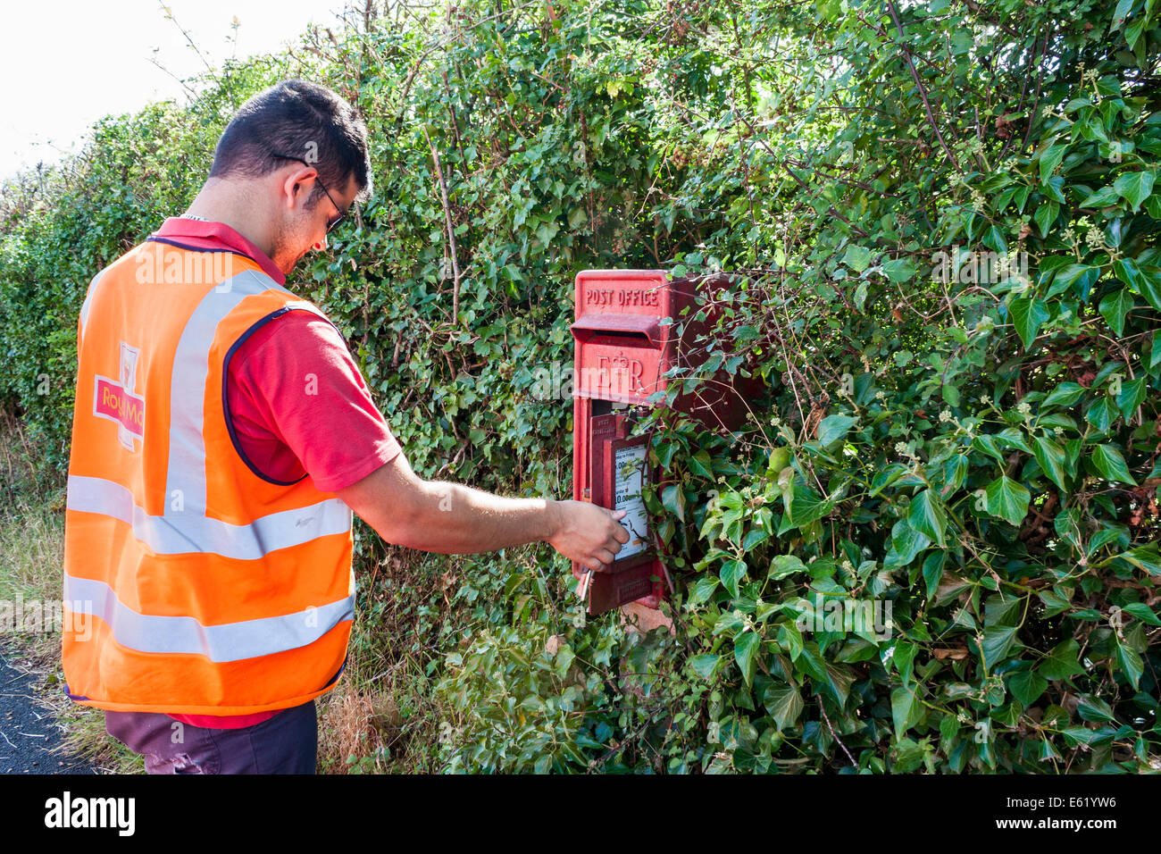 Royal Mail postman collects mail from rural pillar box Stock Photo Alamy