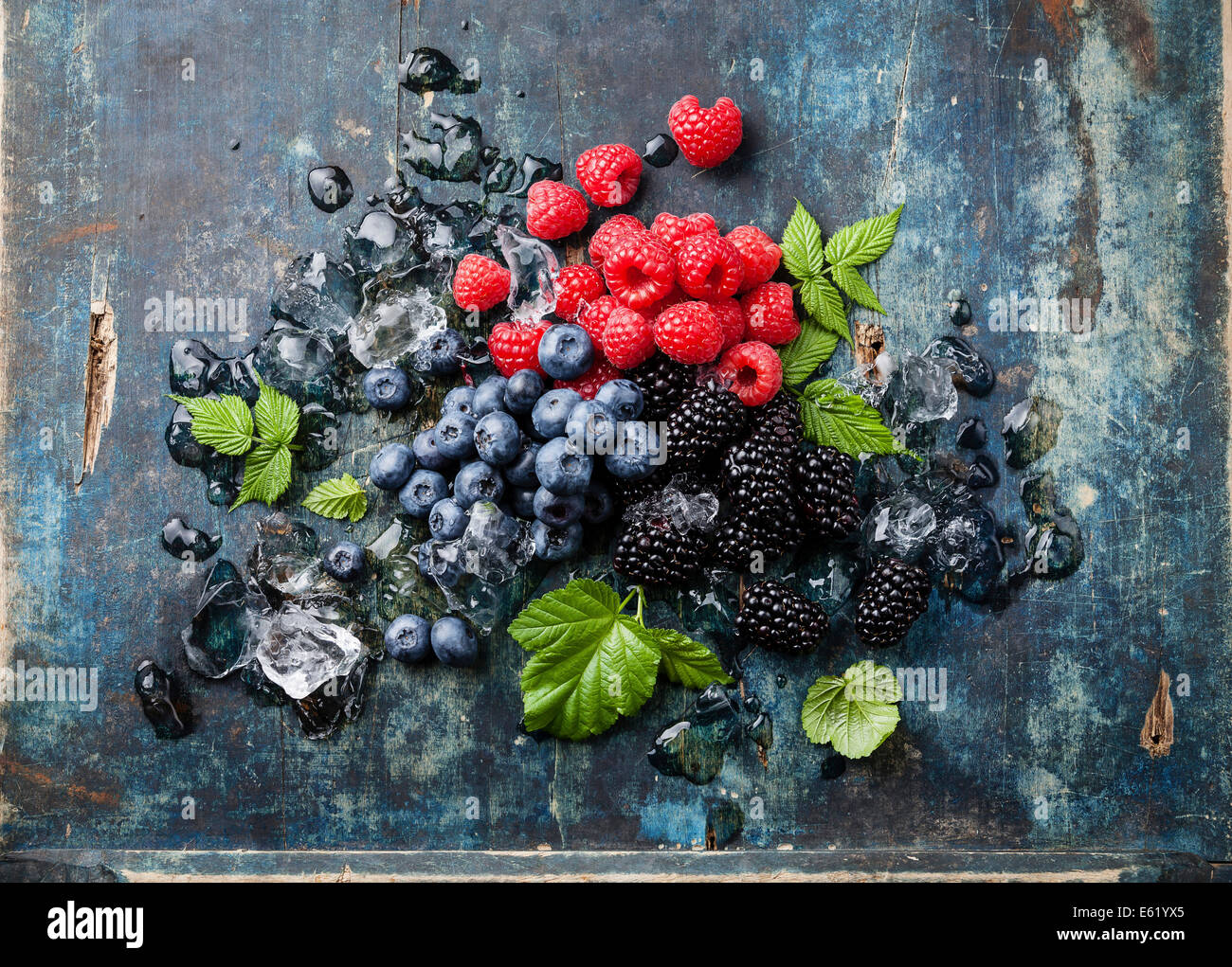 Mix of fresh berries with ice on blue wooden background Stock Photo