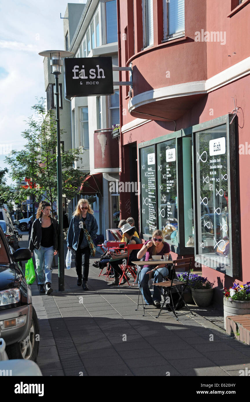 People passing coffee shops, side walk restaurants and pubs in central Reykjavik on a sunny day in Iceland Stock Photo