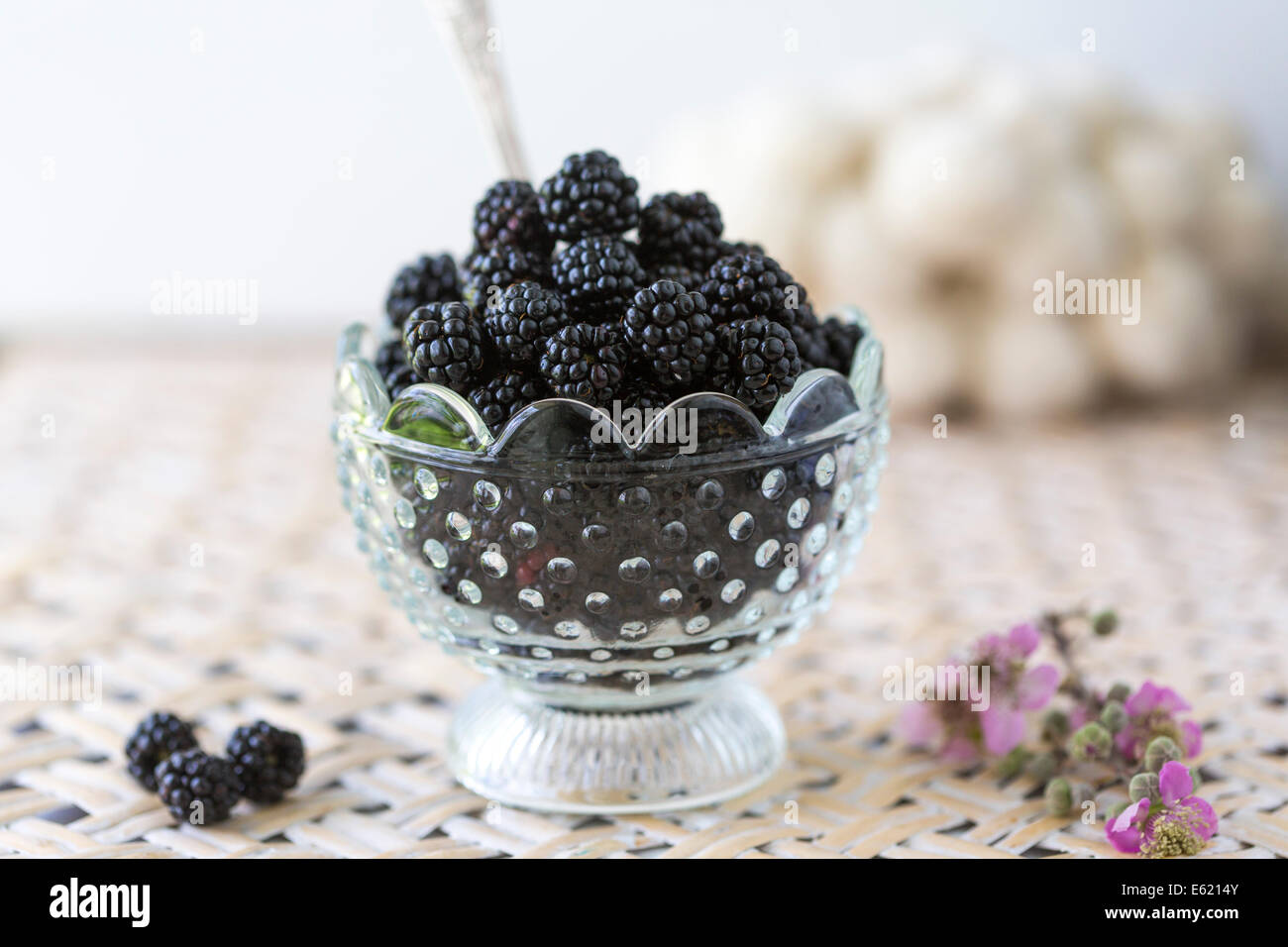 blackberries in glass dish on woven tray with vintage spoon Stock Photo