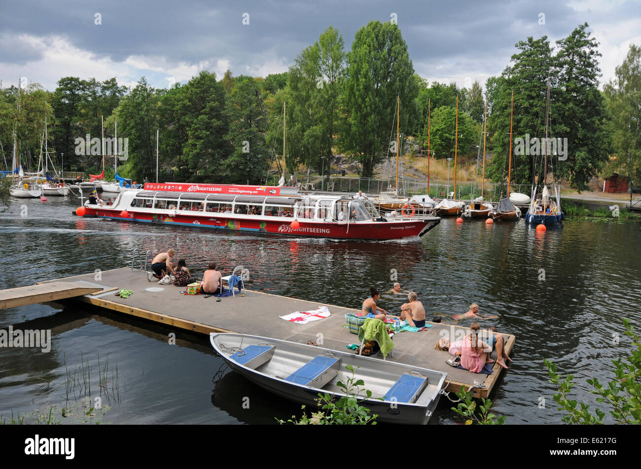 Sightseeing boats and kayakers on Langholmen Långholmen Canal with sunbathers in Stockholm Stock Photo