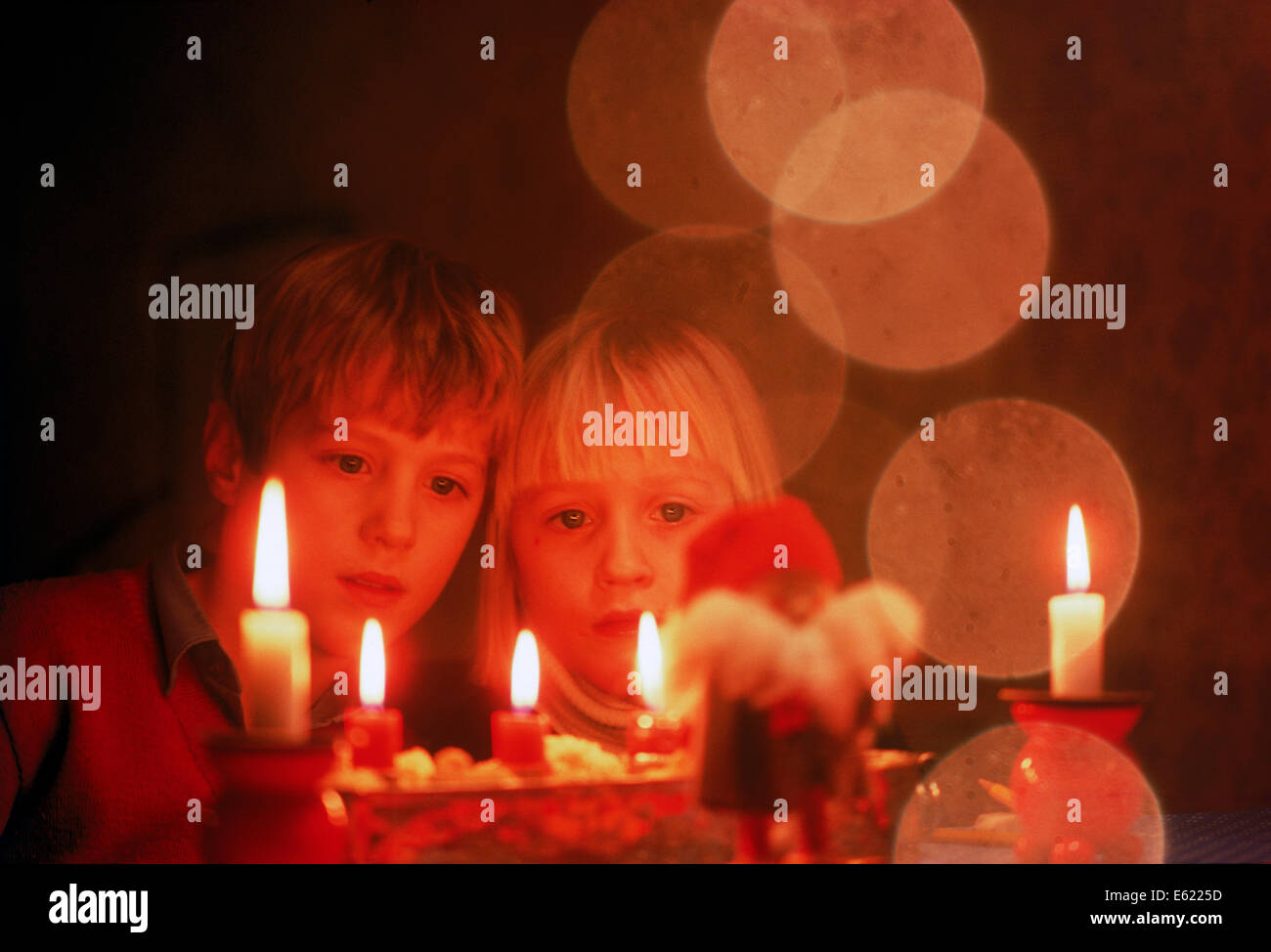 Brother and sister staring at Christmas candles Stock Photo