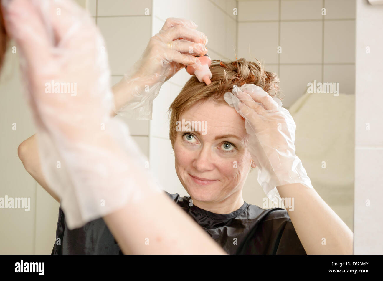 Caucasian Woman With Short Hair Dying Her Hair Red In Front Of
