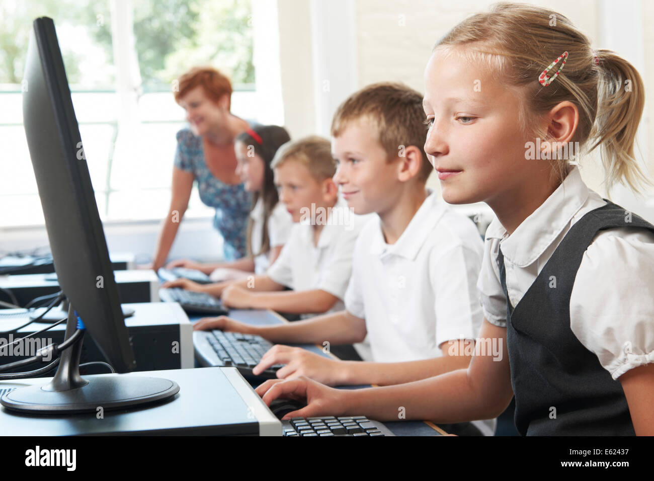Group Of Elementary Pupils In Computer Class With Teacher Stock Photo