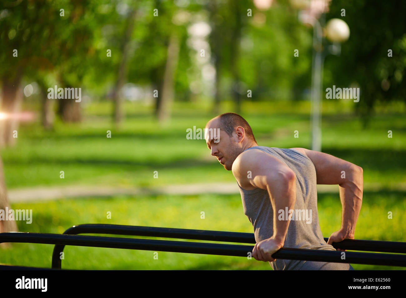 Young man having physical training on sport equipment outside Stock Photo