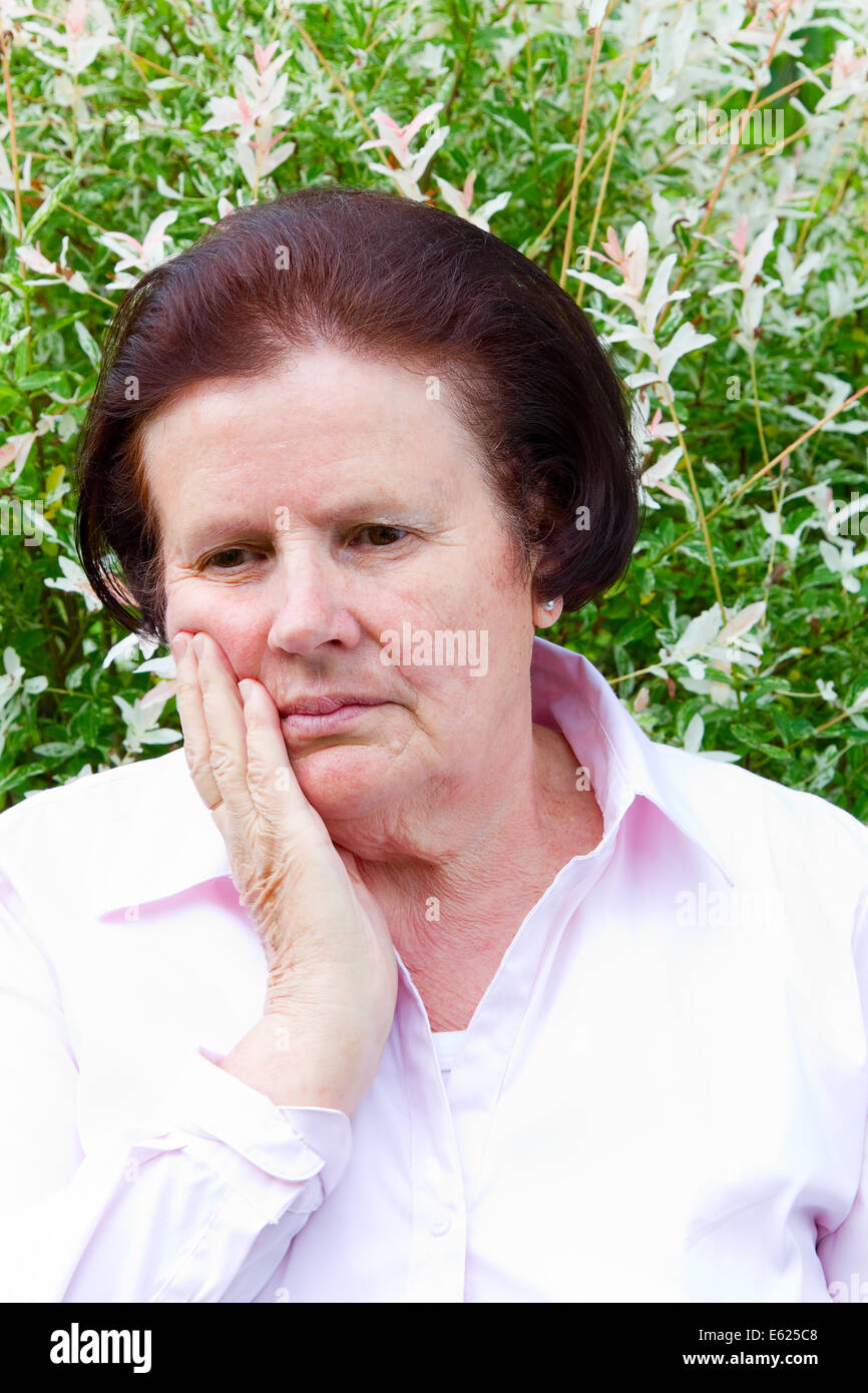 Elderly woman with toothache holding her cheek Stock Photo