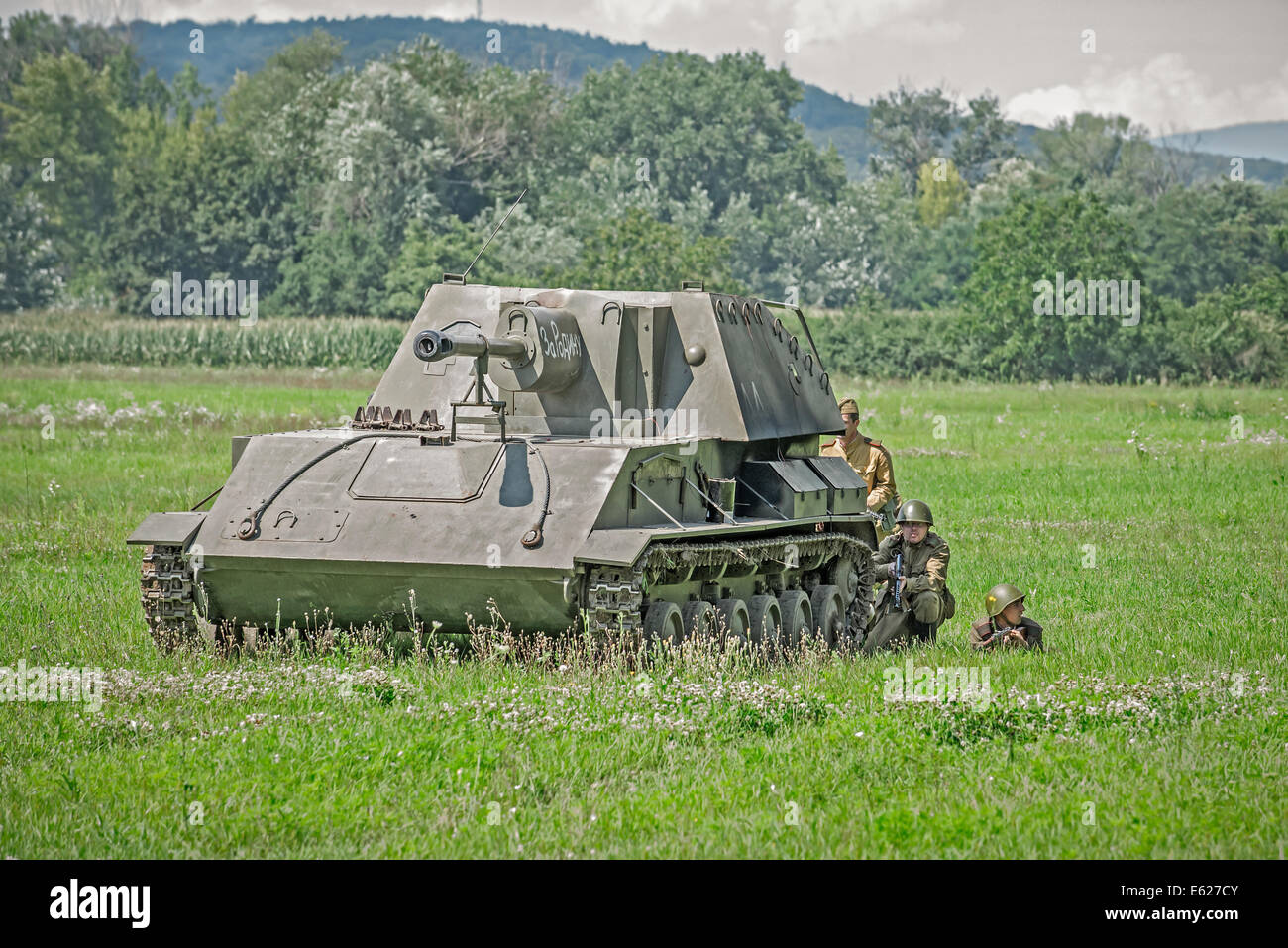 Russian soldiers hiding behind a tank while approaching a battlefield during reenactment of World War II fights in Slovakia Stock Photo