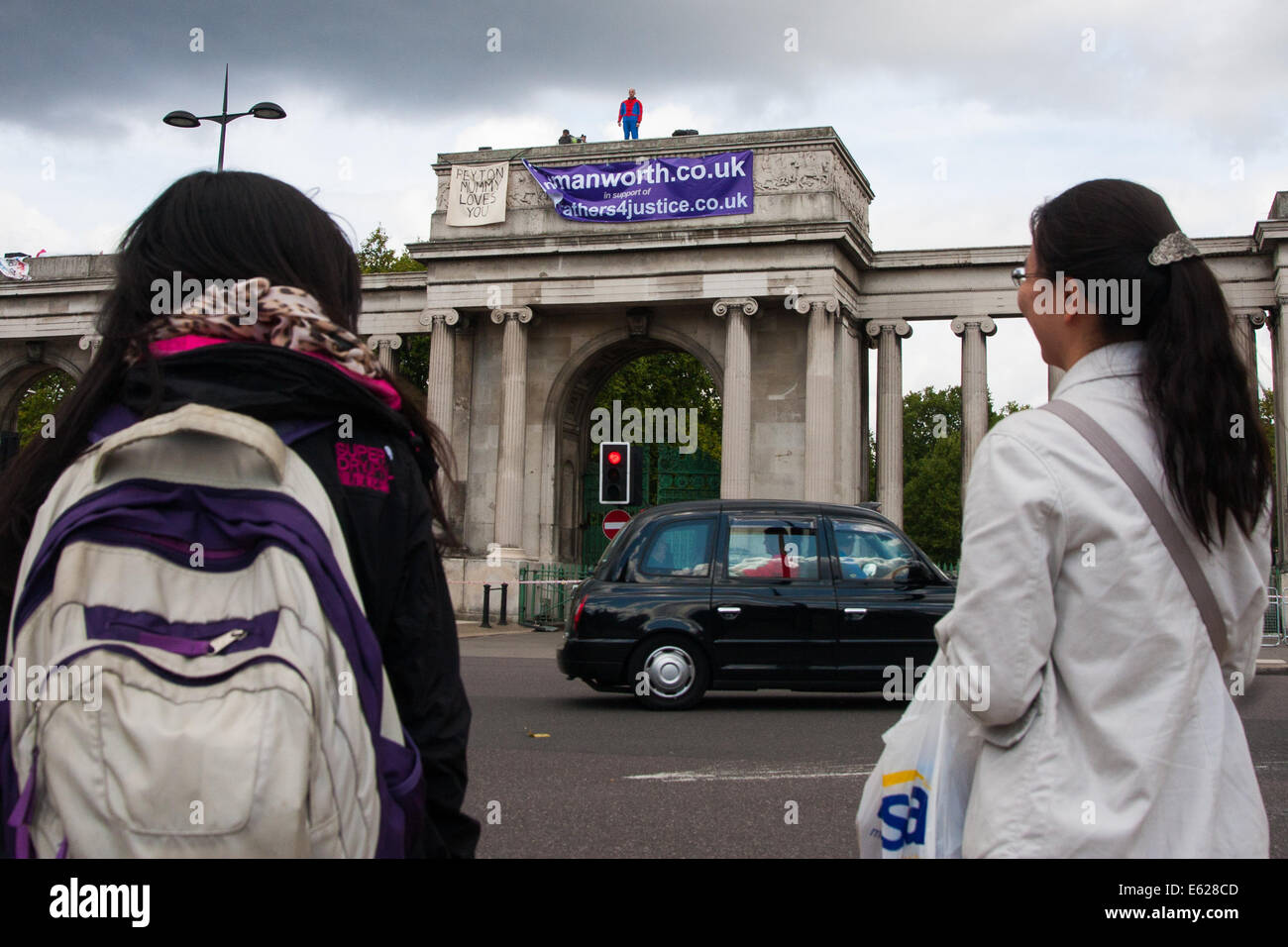 London, August 12th 2014. Tourists look on as protesters from Fathers For Justice demonstrate against separation from their children from the top of   Decimus Burton's Ionic screen entrance to Hyde Park adjacent to Apsley House at  Hyde Park Corner. Credit:  Paul Davey/Alamy Live News Stock Photo