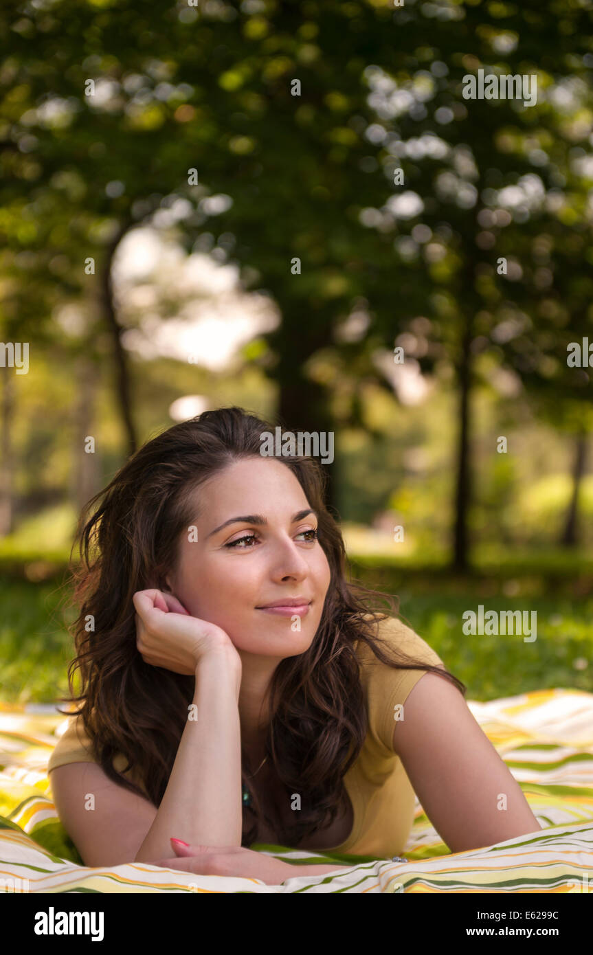 Portrait of a beautiful young woman lying on the grass at park Stock ...