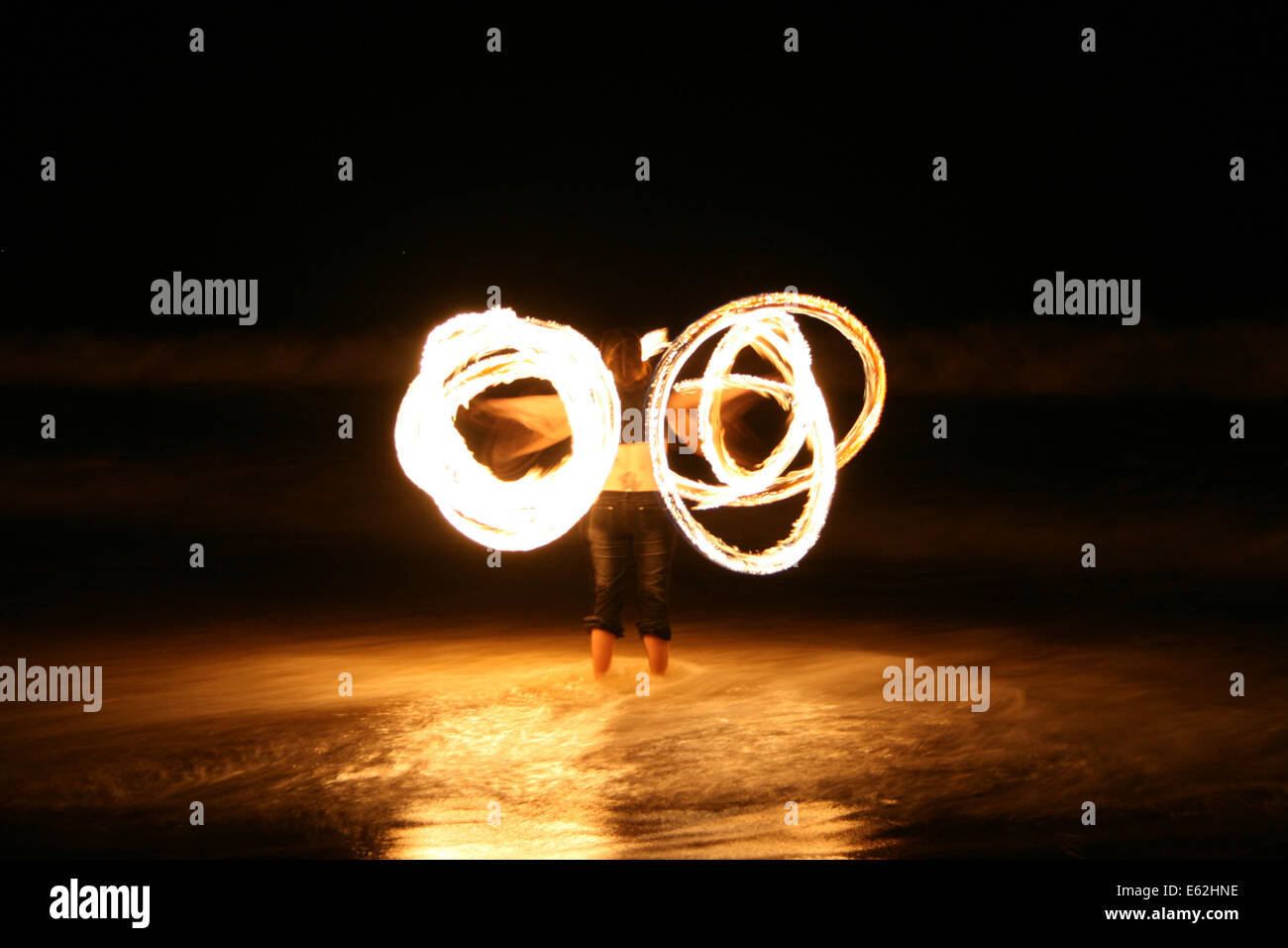 A Fire Dancer twirls on Nobby's Beach to celebrate the lunar eclipse Stock Photo
