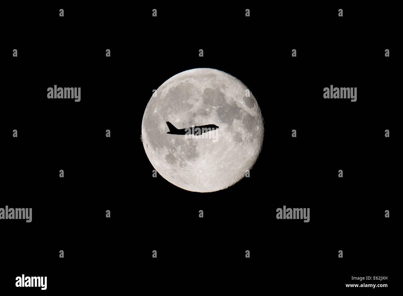 Aeroplane flying across a full moon Stock Photo