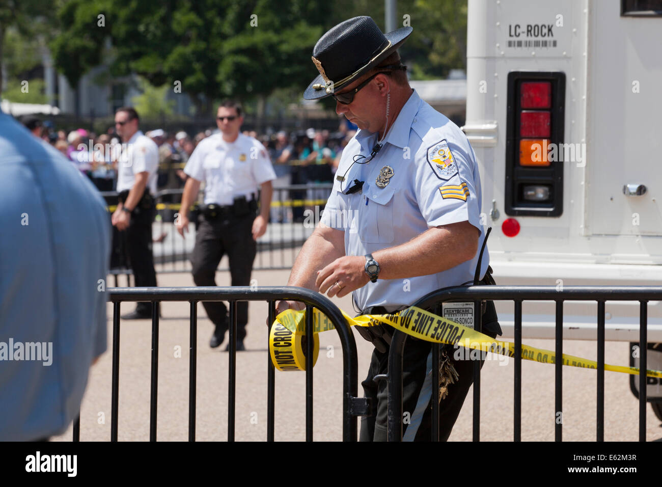 Policeman tying police line tape on barricade fence - Washington, DC ...
