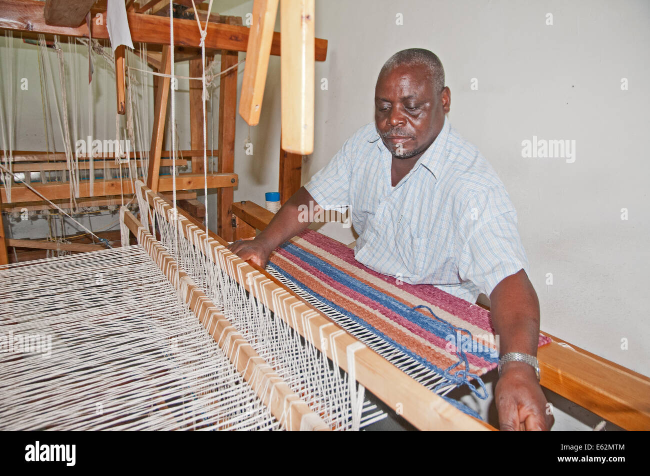 Black African man weaving a woollen rug on loom at Elmentieta Weavers