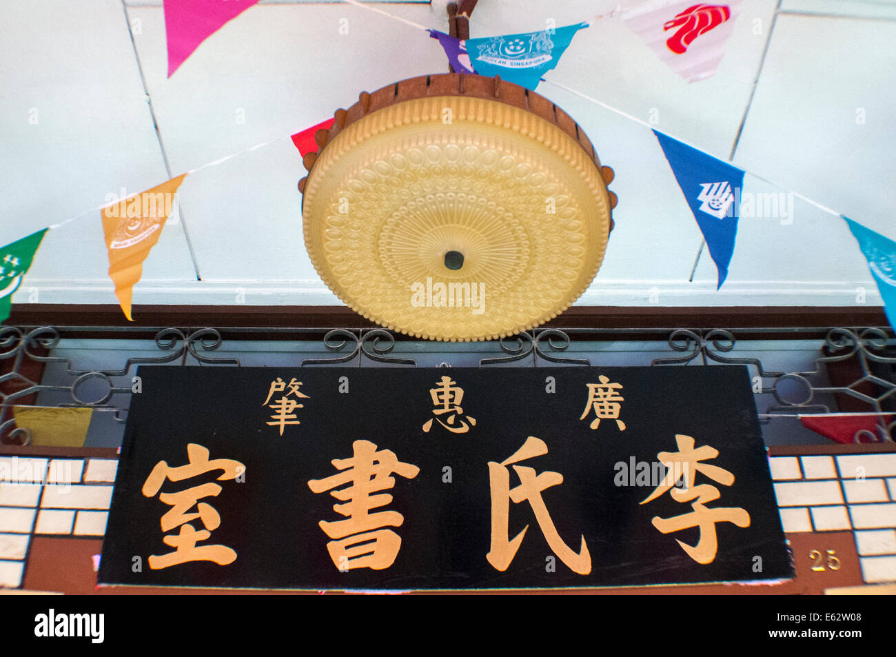 Sign and National Day pennants above a traditional Chinese storefront in Singapore Stock Photo