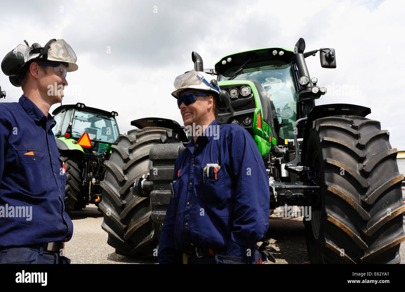 two mechanics, workers with large tractor outlet Stock Photo