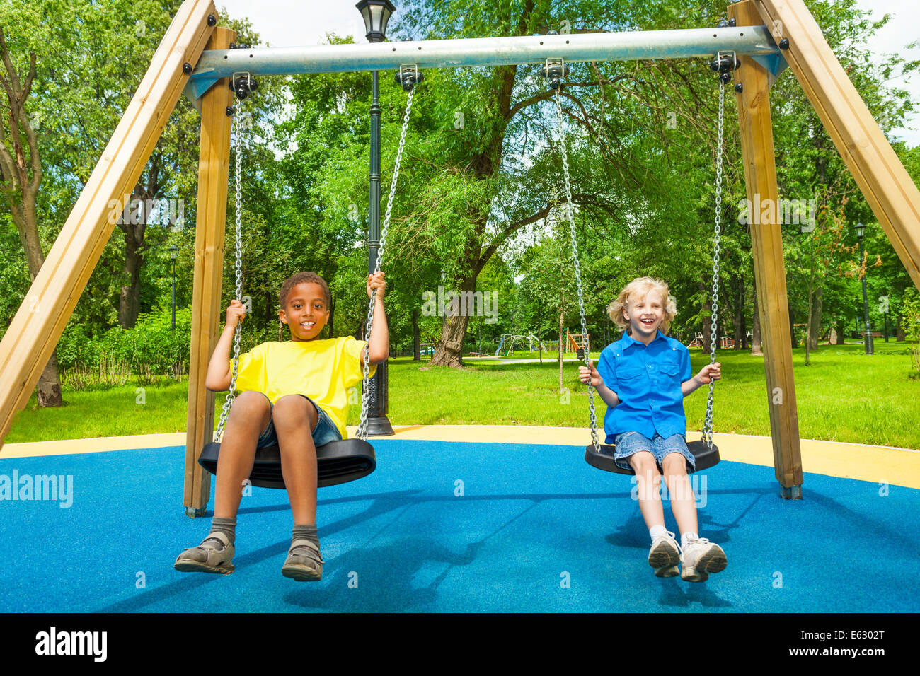 Two boys swing together and hold chains of swings Stock Photo Alamy