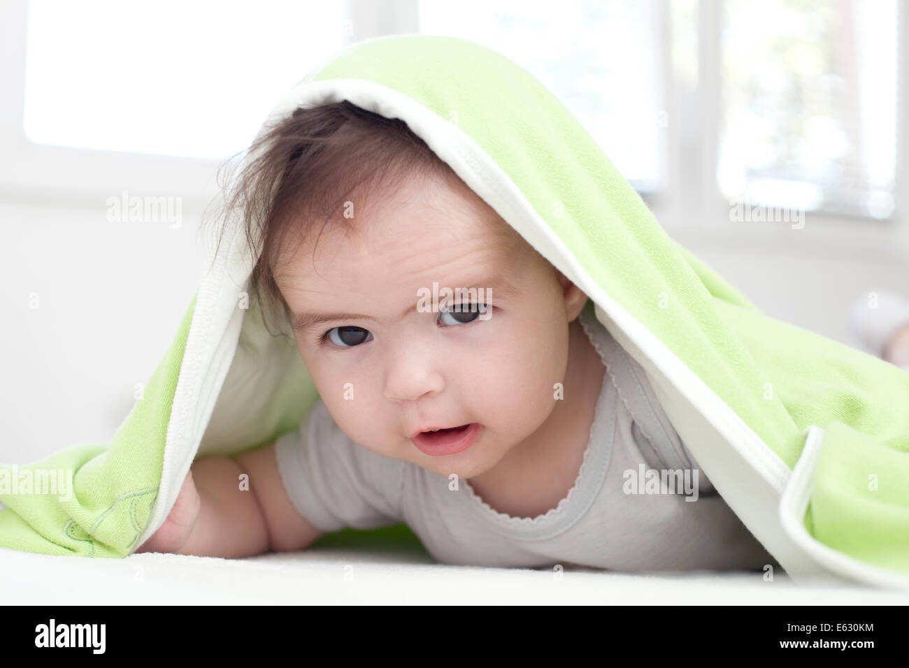Baby girl is hiding under the white and green blanket Stock Photo Alamy