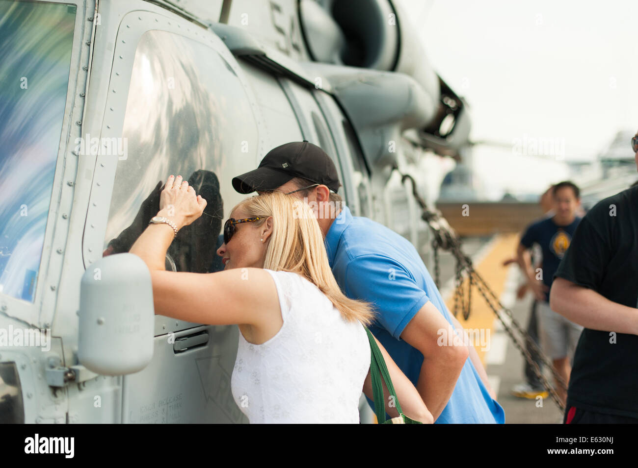 A couple admire the cockpit of a Sikorsky SH-60 Seahawk aboard the USS Essex. Stock Photo